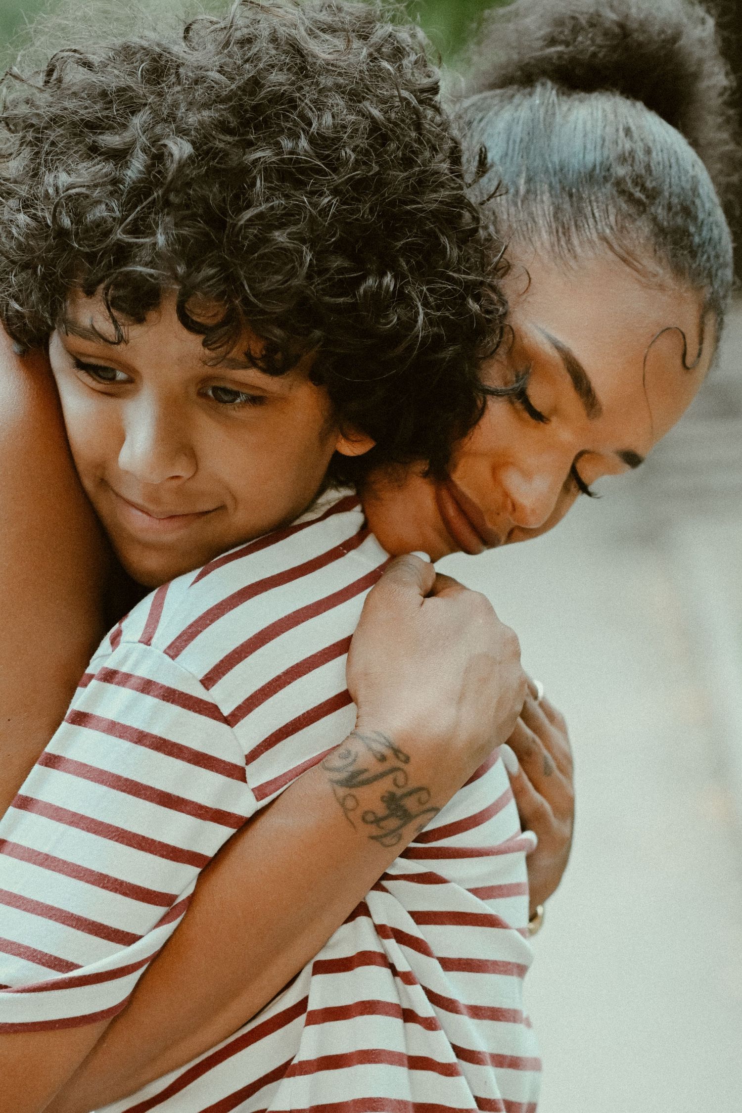 Two people hugging and wearing matching striped shirts share an intimate moment in a close-up photo.