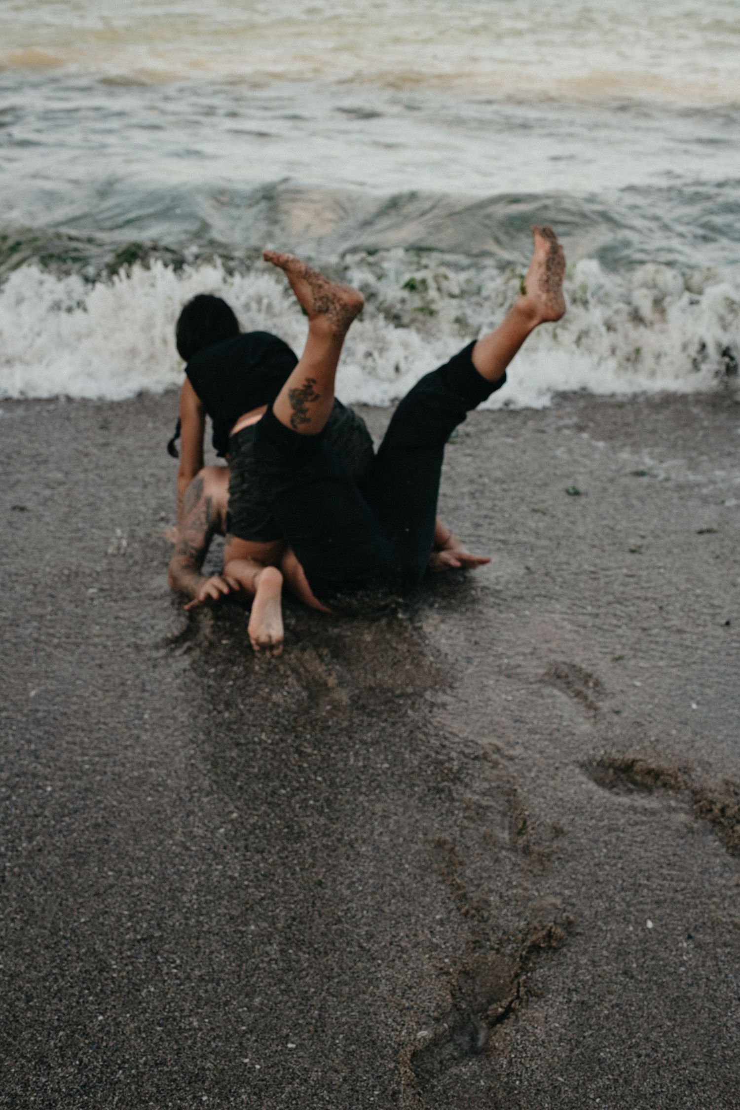 Playful scene of people splashing in the ocean waves on a sandy beach.