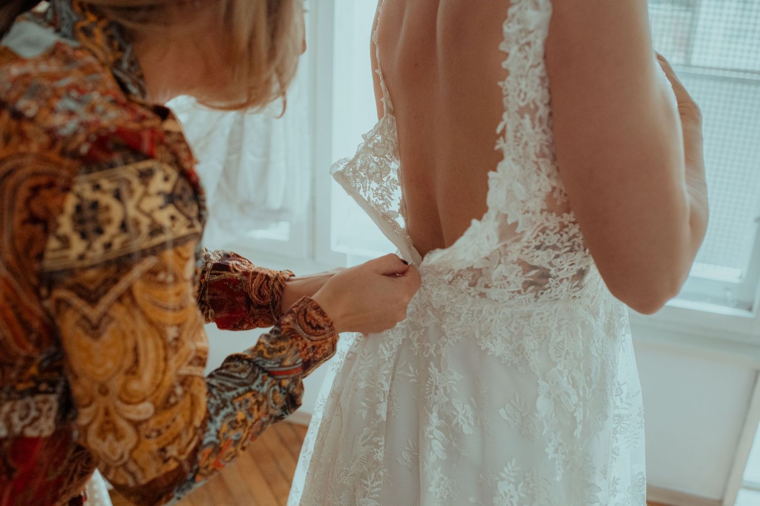 Detail shot of an elegant white lace wedding dress in a bright room.