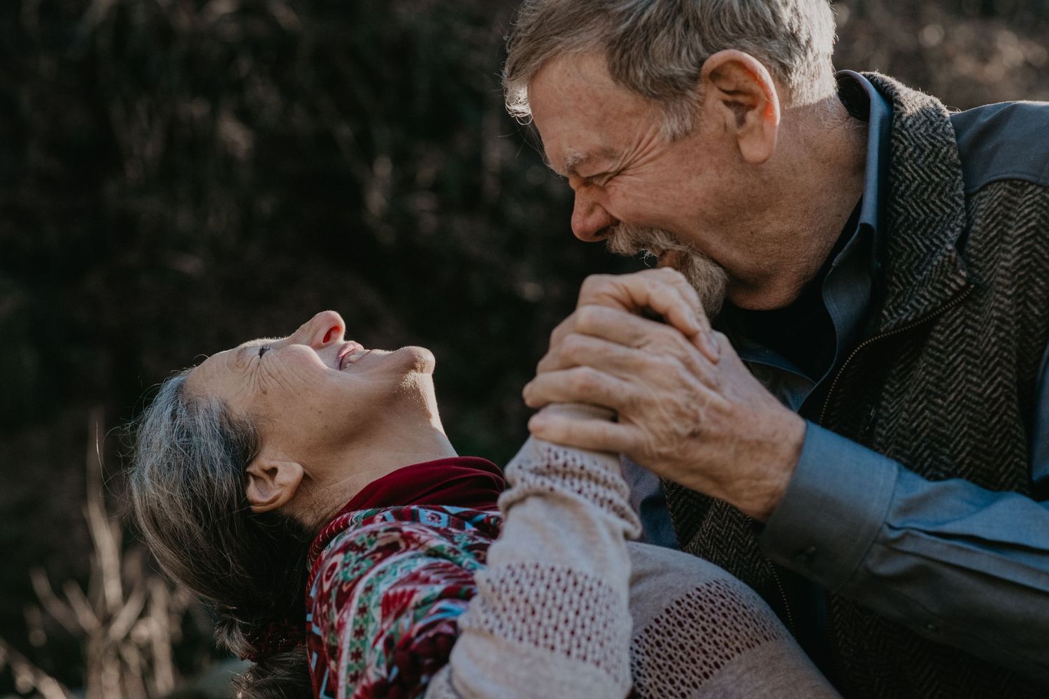 A joyful candid moment shared between a senior and younger person laughing together outdoors.