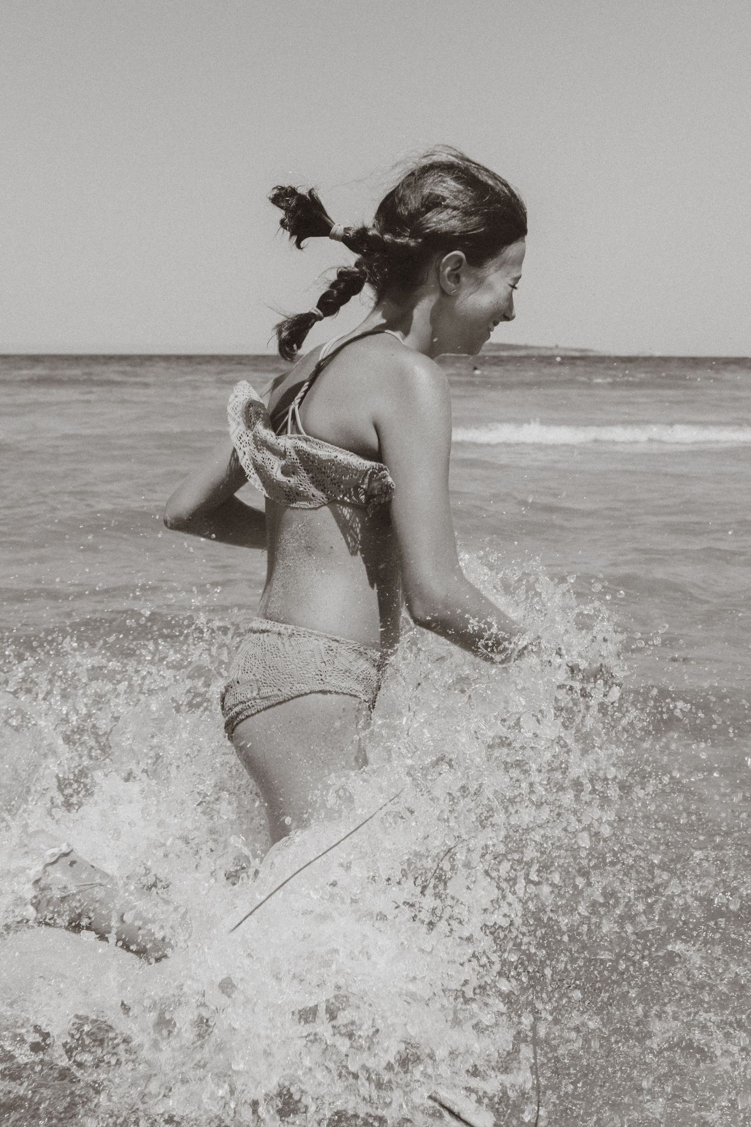 Black and white sequence of someone jumping through ocean waves at the beach.