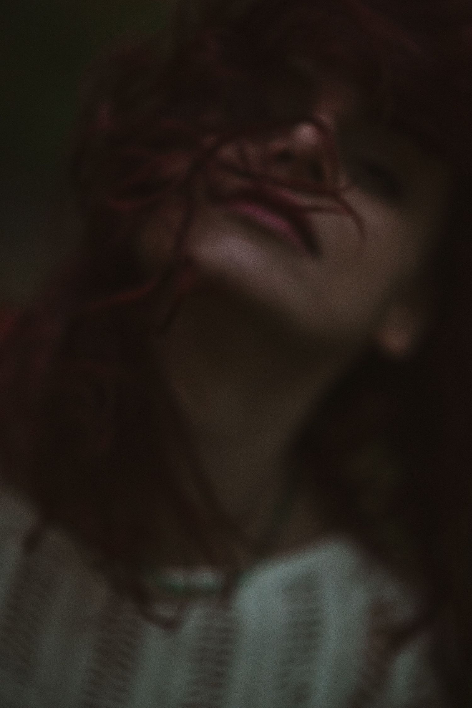 Moody low-light portrait with dark shadows and turquoise tones.