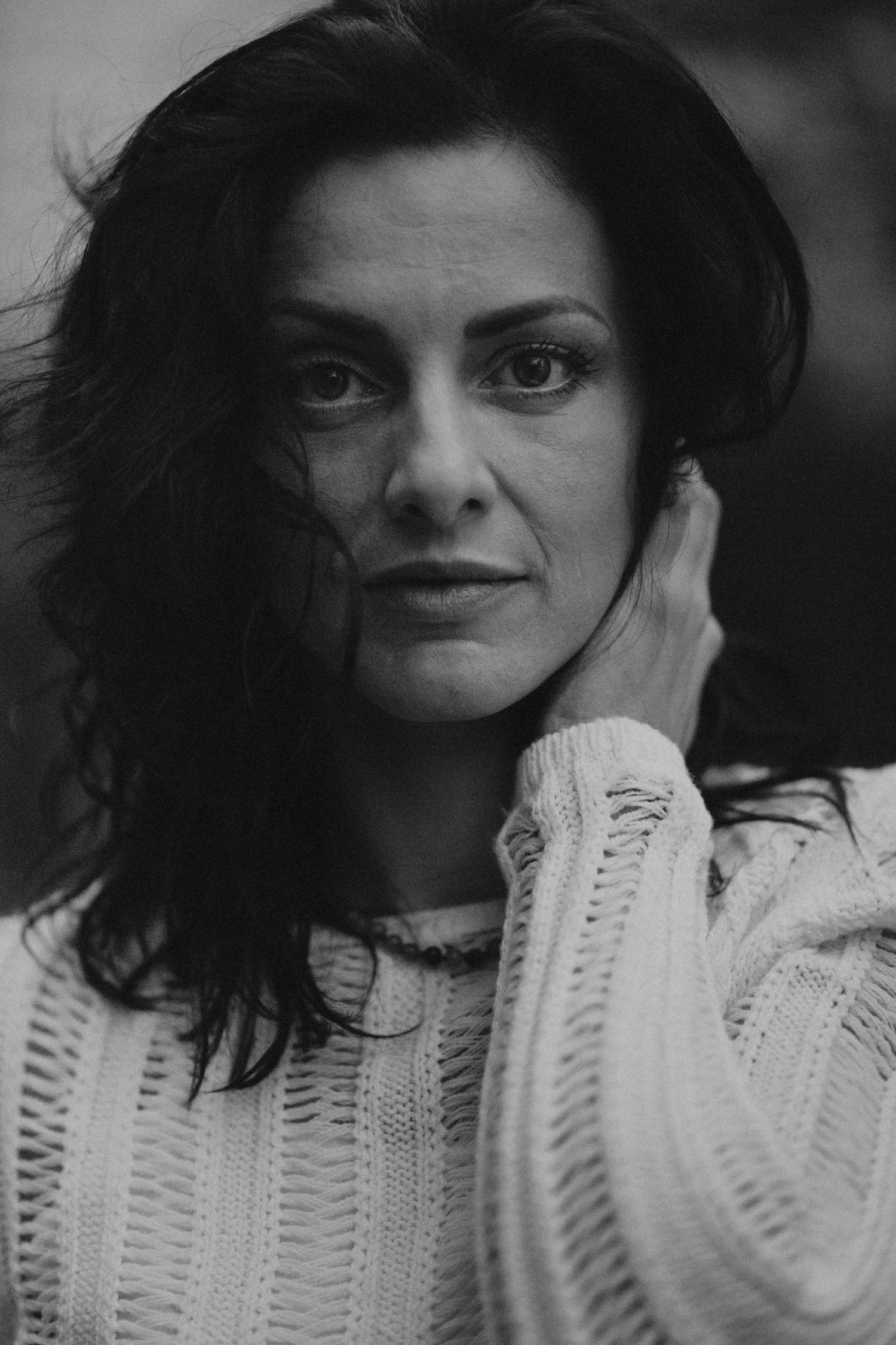 Black and white portrait series showing expressive close-up shots behind white knit fabric.