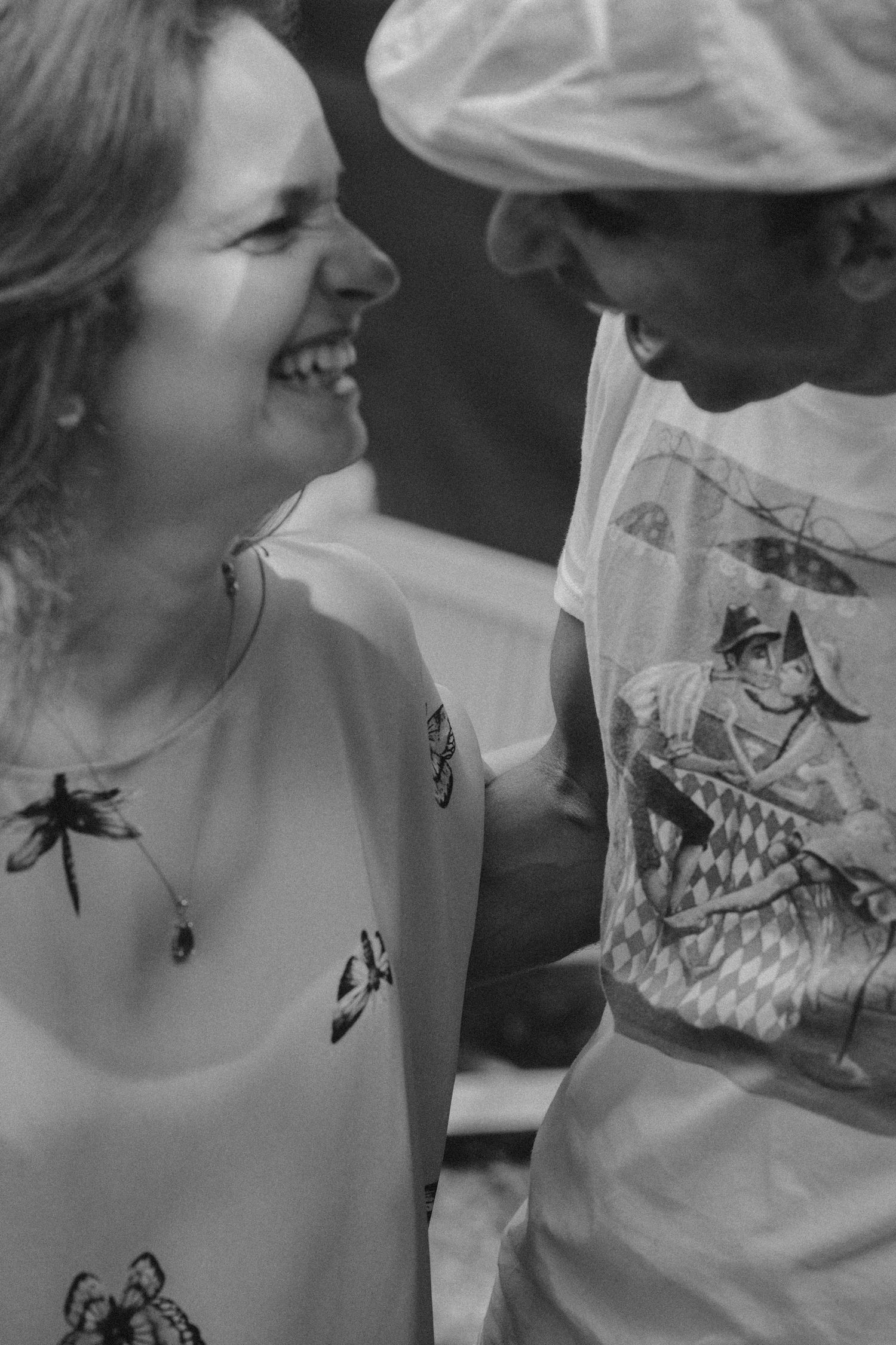 Black and white photo of a couple sharing a lighthearted moment wearing casual attire.