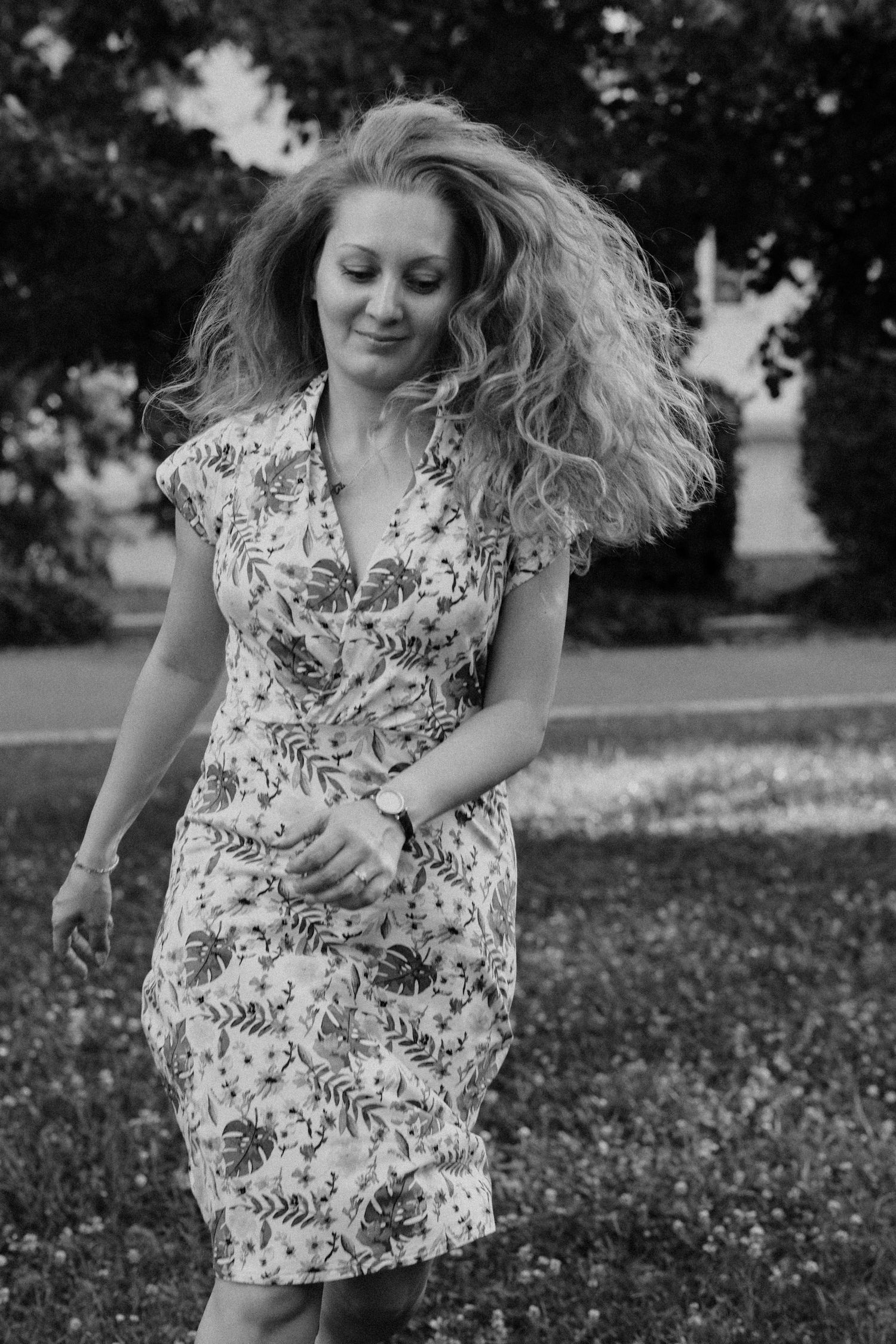 Black and white sequence of someone twirling in a floral dress in a park setting.