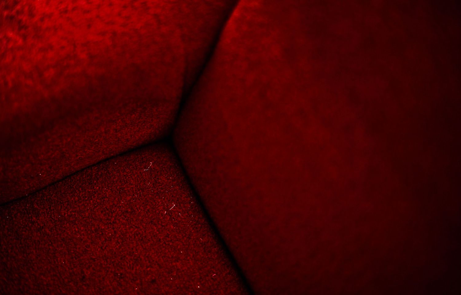 Abstract close-up of deep red velvet fabric texture in dramatic lighting.