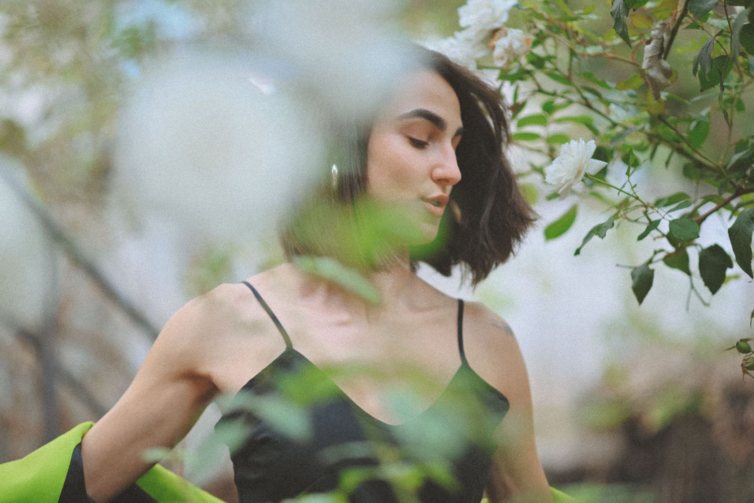 Artistic portraits in natural setting with soft bokeh and green foliage.