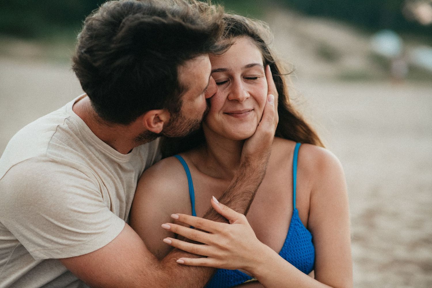 Tender moment captured between couple at the beach during golden hour.