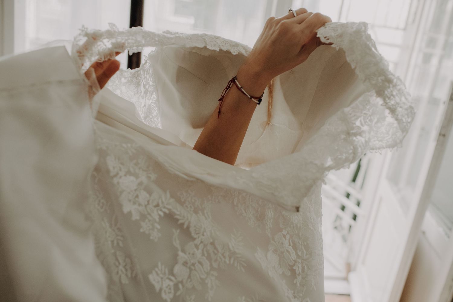 Close-up detail of intricate lace embroidery on a white wedding dress.