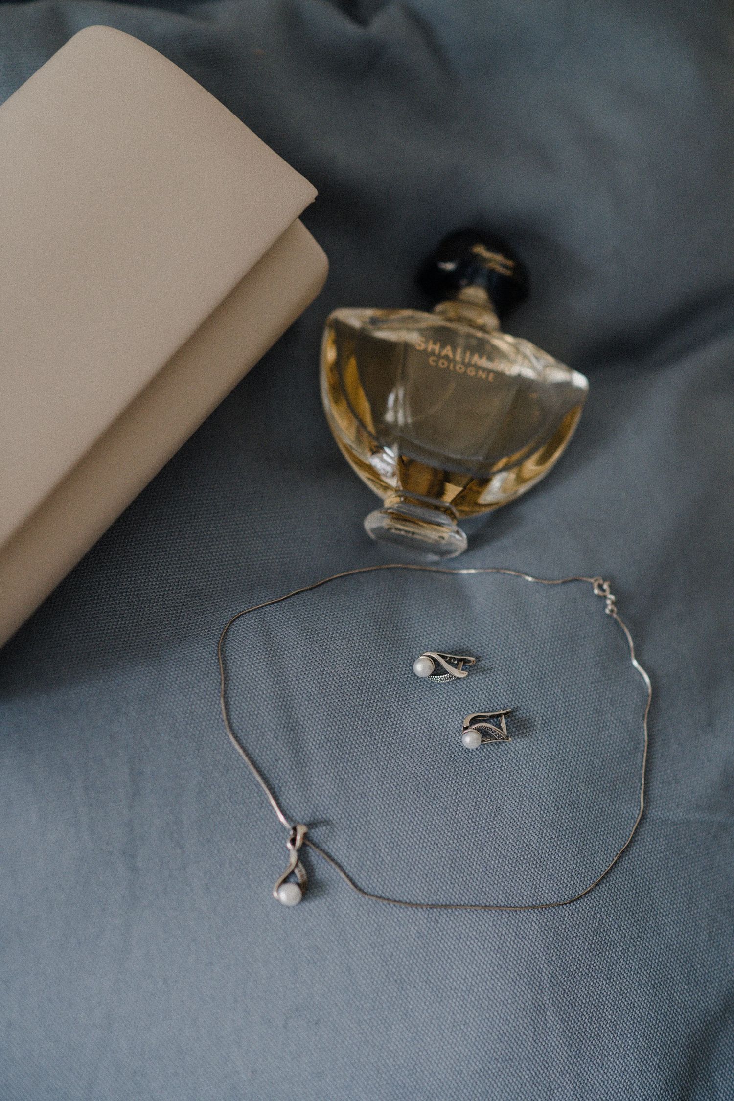 Delicate silver jewelry and accessories arranged on a gray textile background.