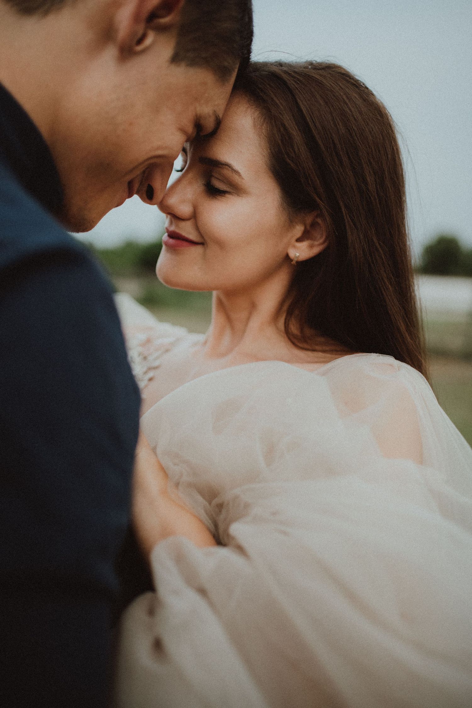 Intimate moment between newlyweds sharing a tender embrace in warm evening light.