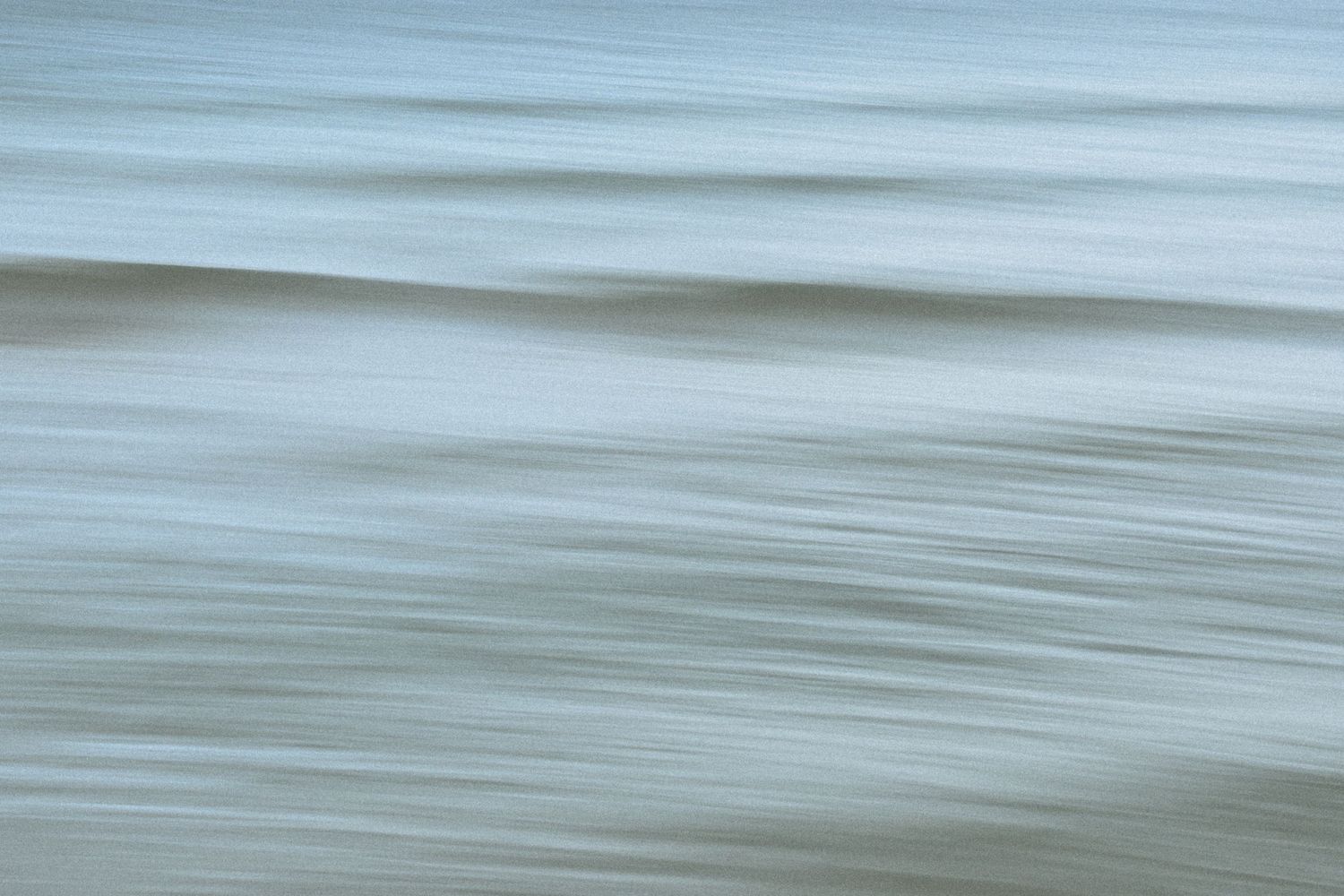 Minimalist ocean landscape with smooth blue water creating horizontal motion blur.