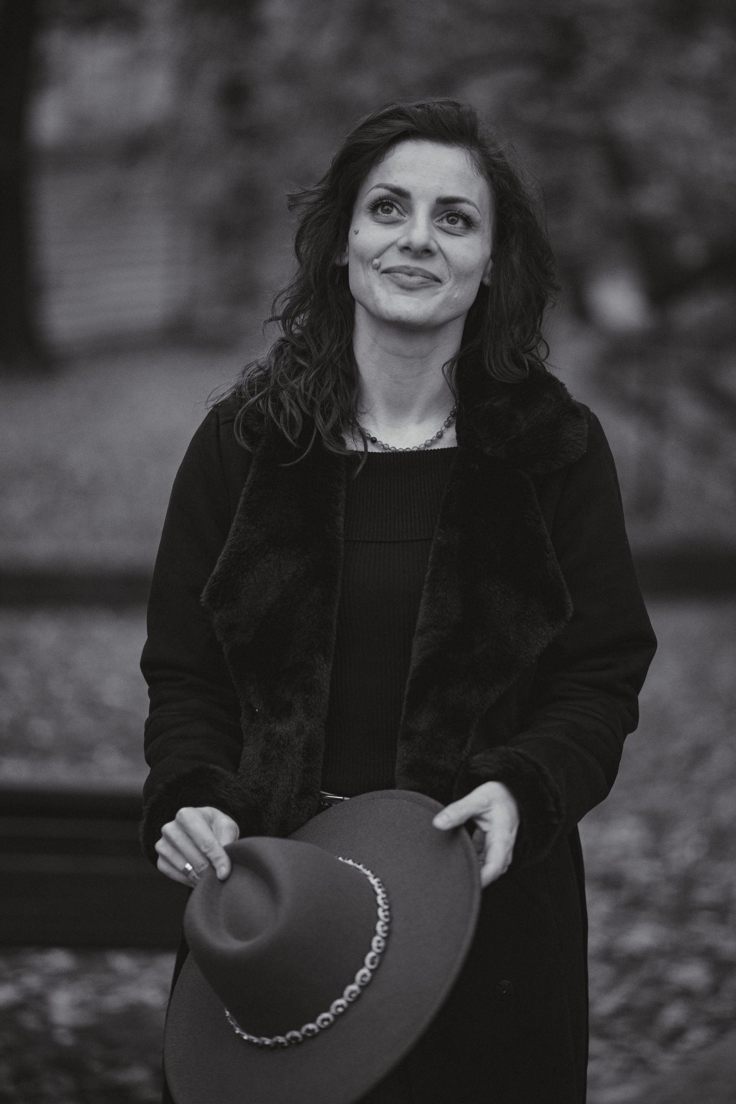 Monochrome outdoor portrait of someone holding a decorative hat.