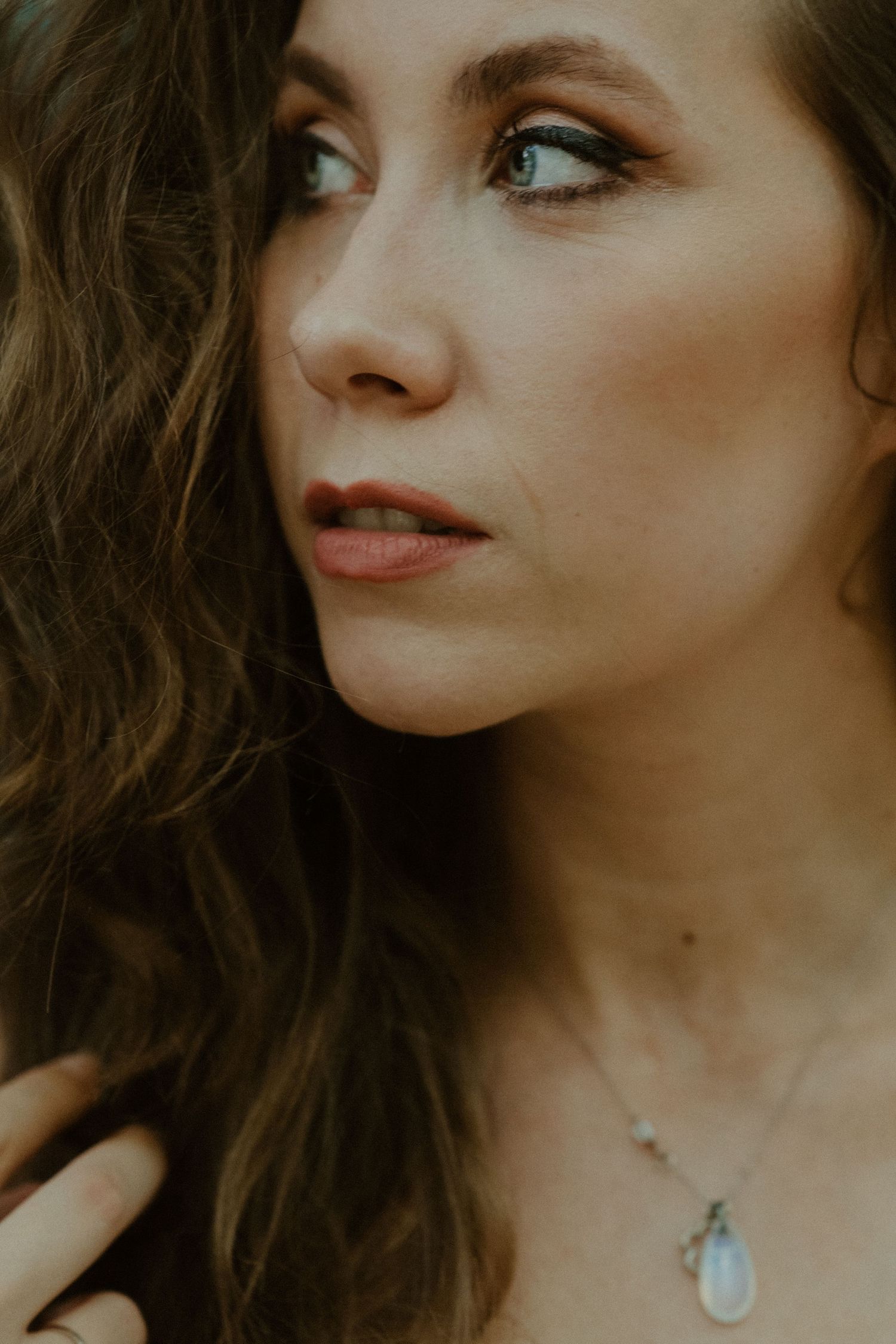 An artistic portrait capturing someone in profile view with dramatic lighting and natural makeup.