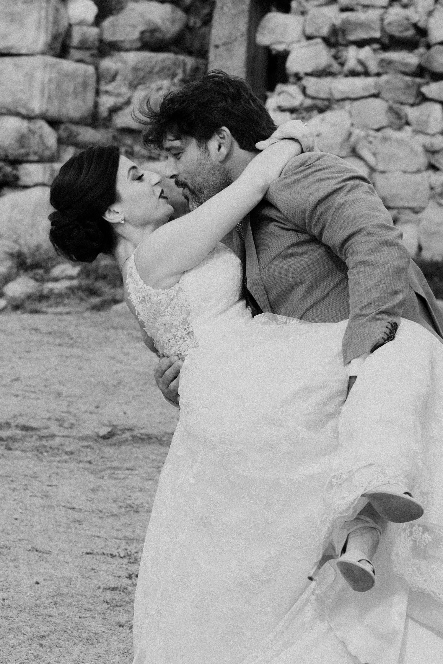 A romantic moment captured in black and white against a stone wall backdrop.