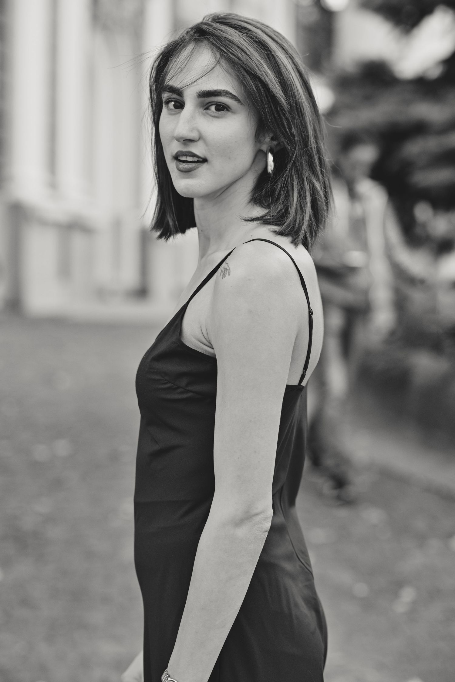 Black and white fashion portraits in urban setting showing elegant poses in sleeveless dress.