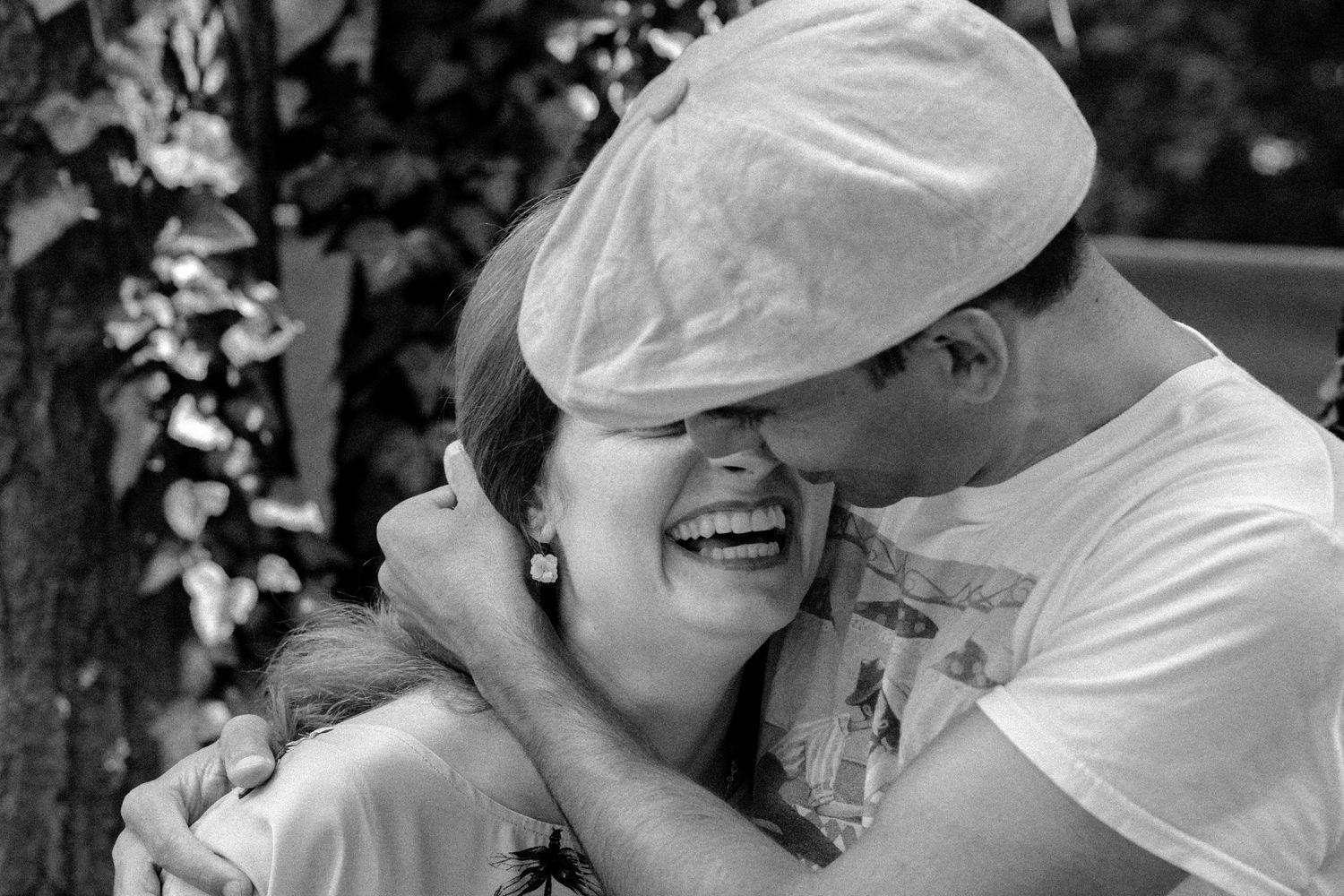 Black and white portrait capturing a joyful, candid moment of laughter outdoors.