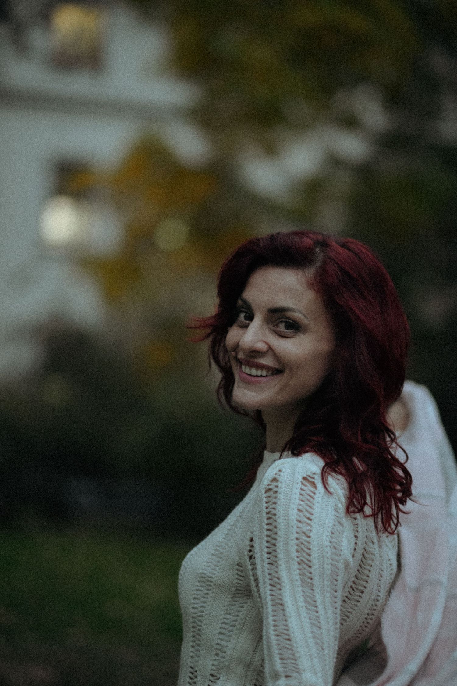 Portrait of someone in a white knit sweater during golden hour outdoors.