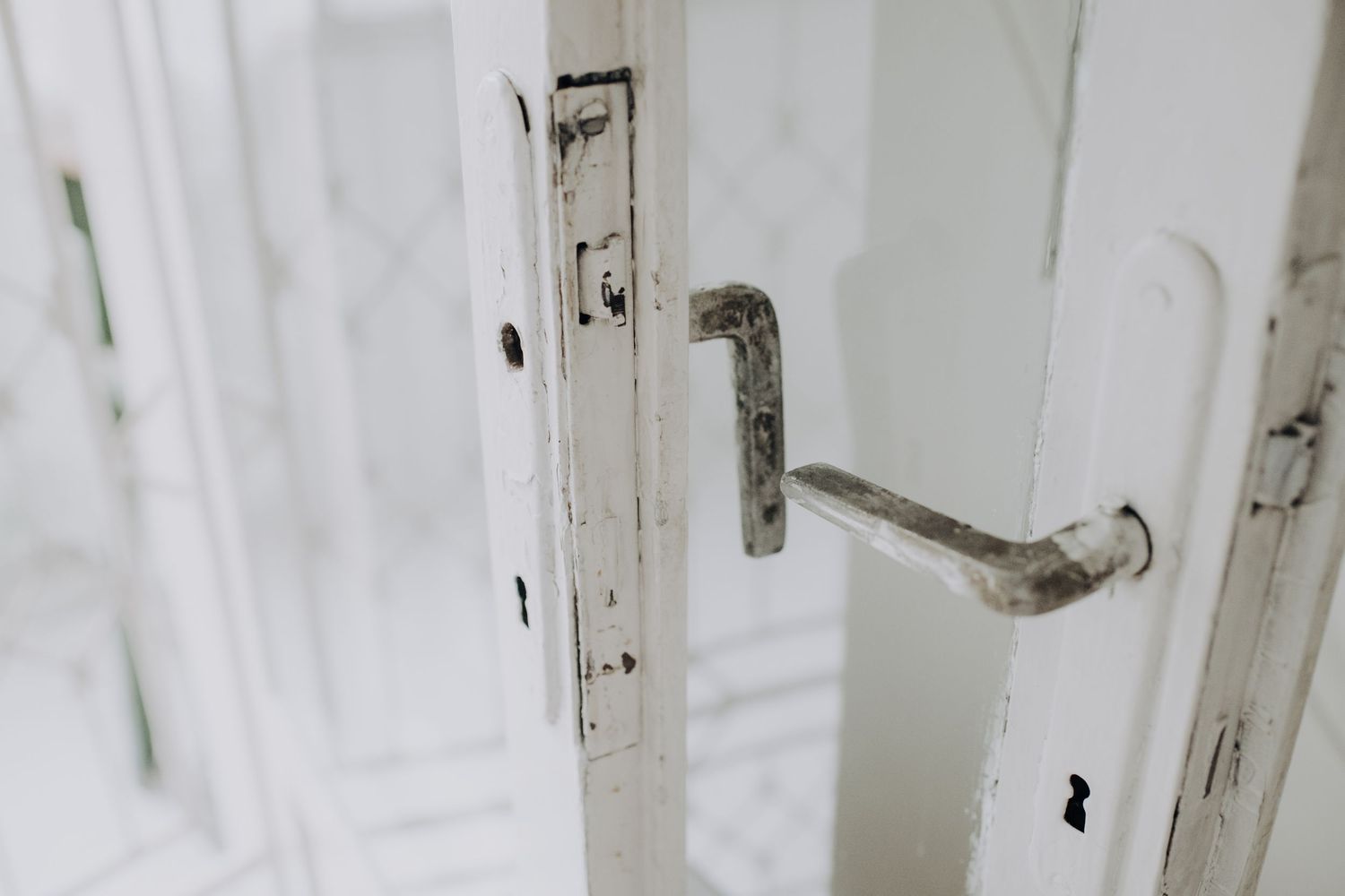 Weathered white door handle and lock mechanism showing signs of age and wear.