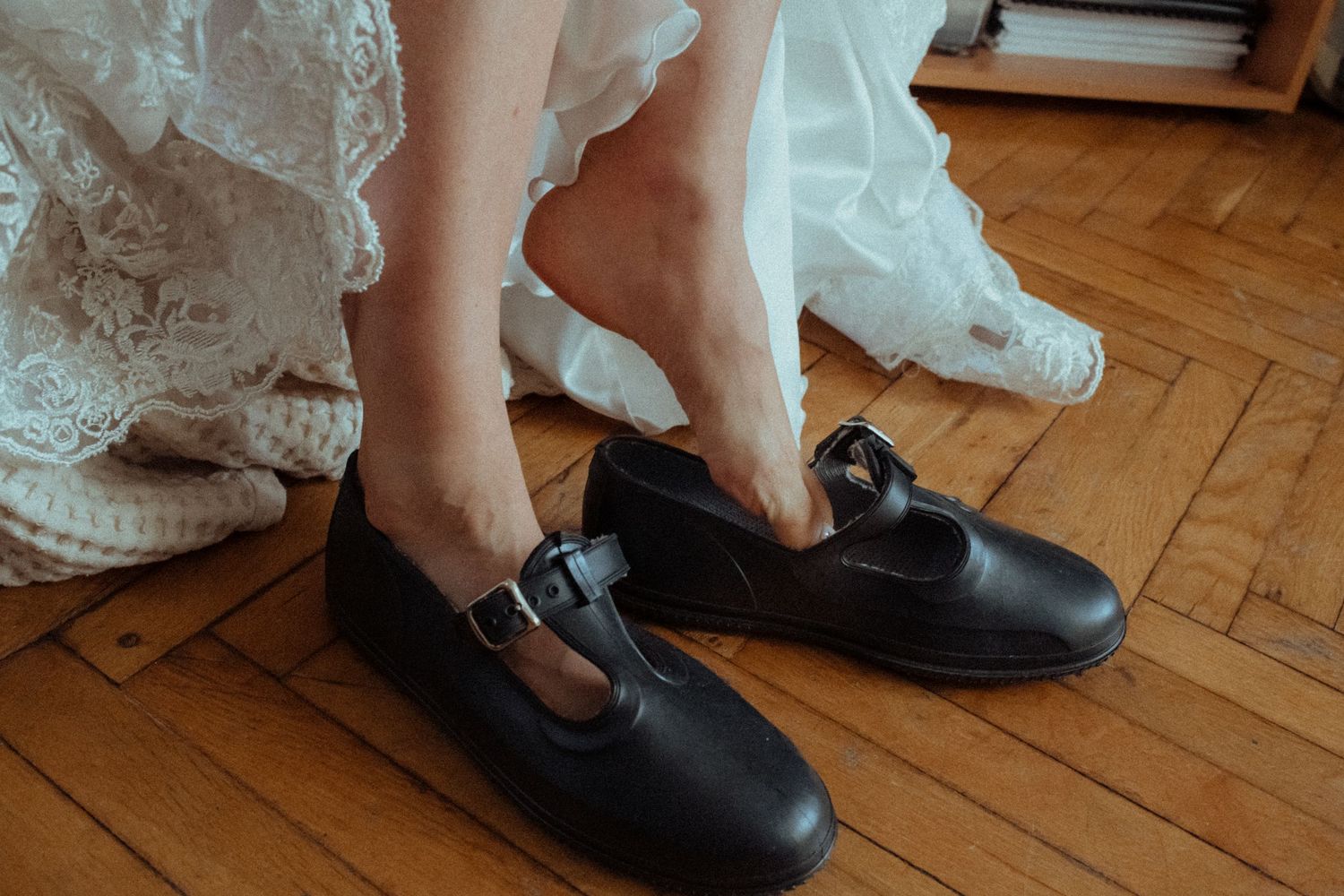 Close-up view of feet wearing formal black shoes on a wooden floor.
