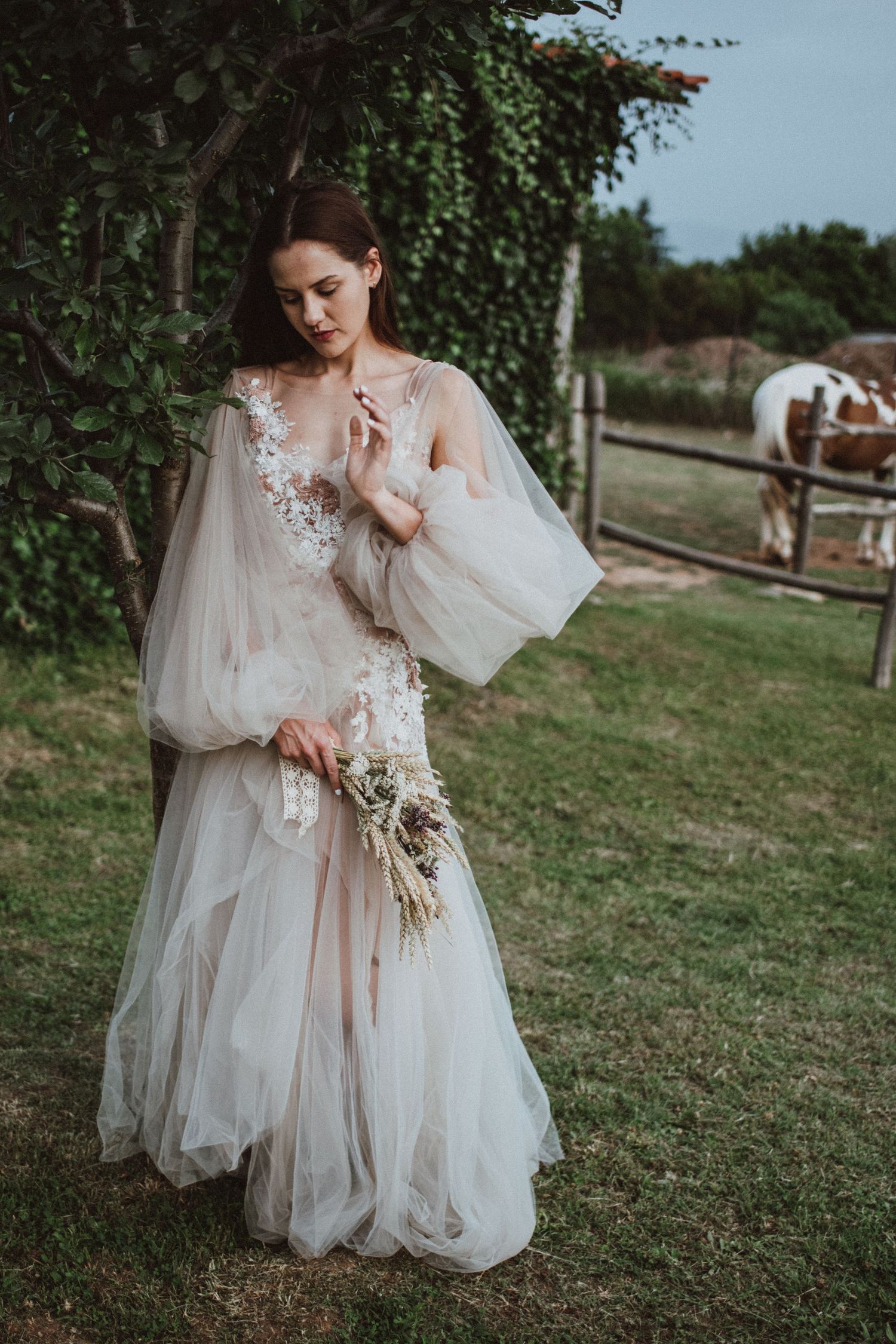 Ethereal bridal portrait featuring a flowing tulle dress with floral details in a garden setting.