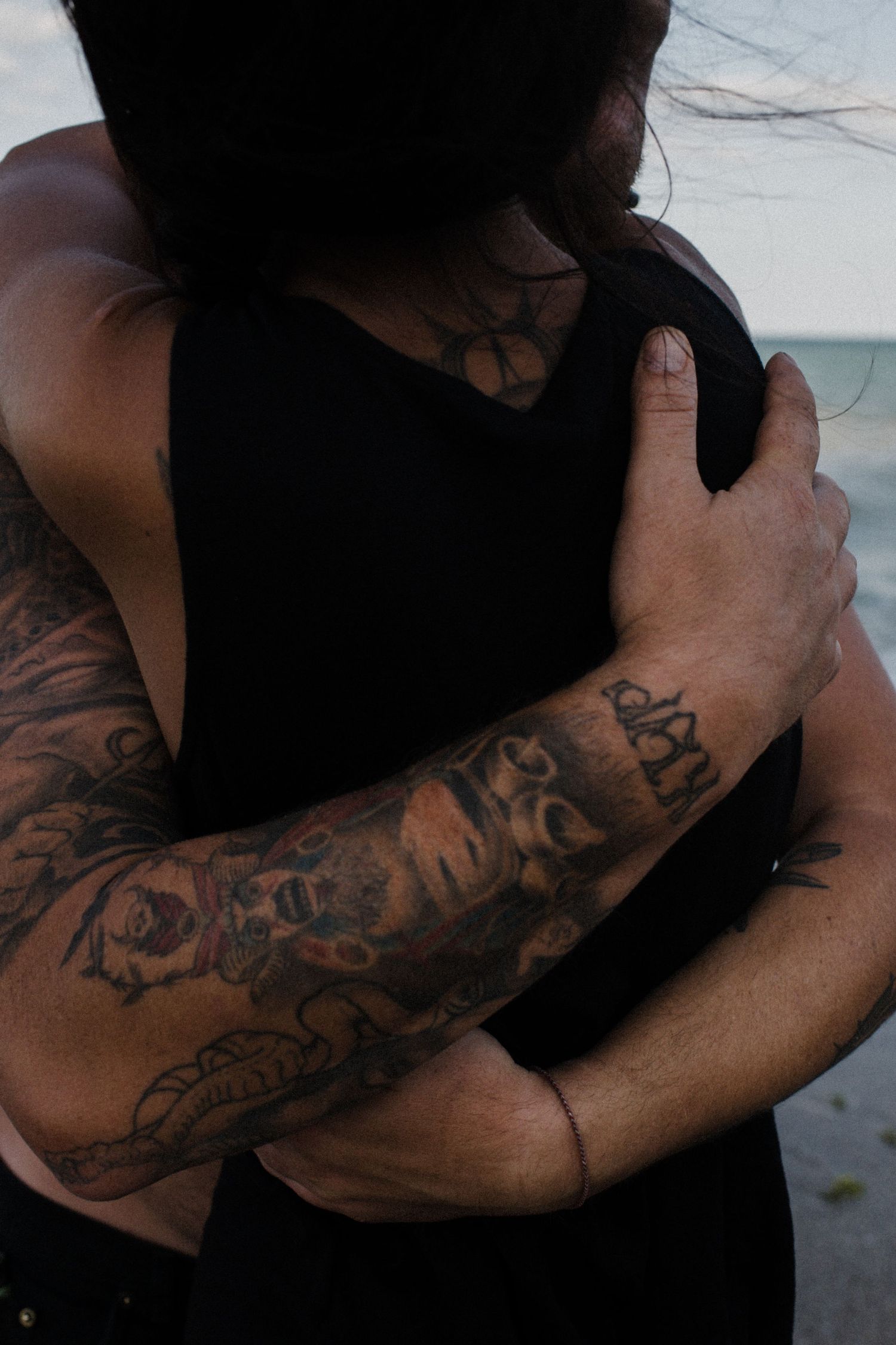 Close-up of an embrace showing detailed tattoo sleeve art on arm.