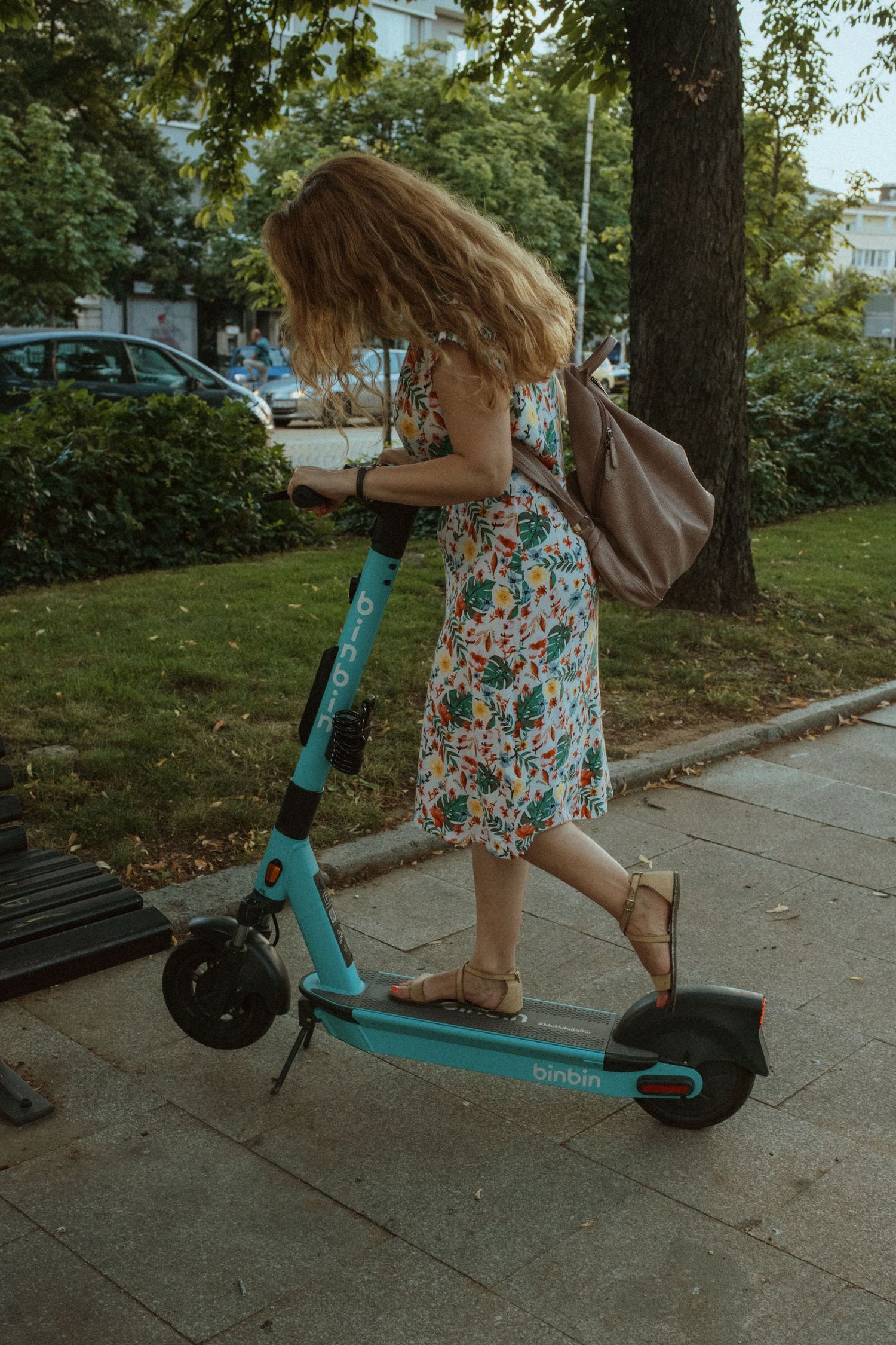 Action shots of someone riding a turquoise electric scooter while wearing a floral dress.