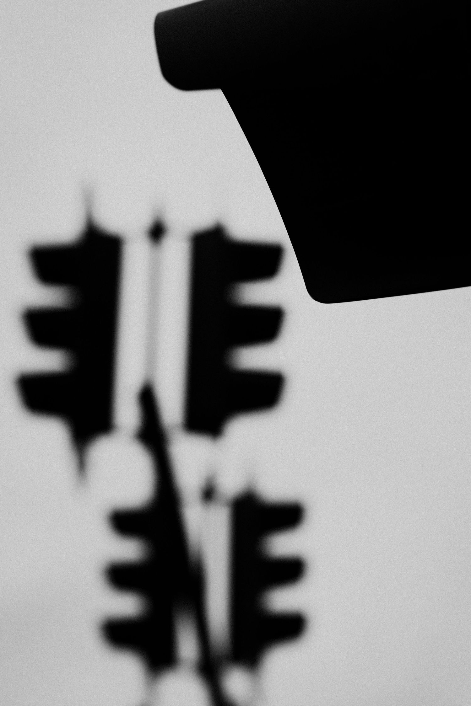 Silhouette of traffic light signals against bright minimal background.
