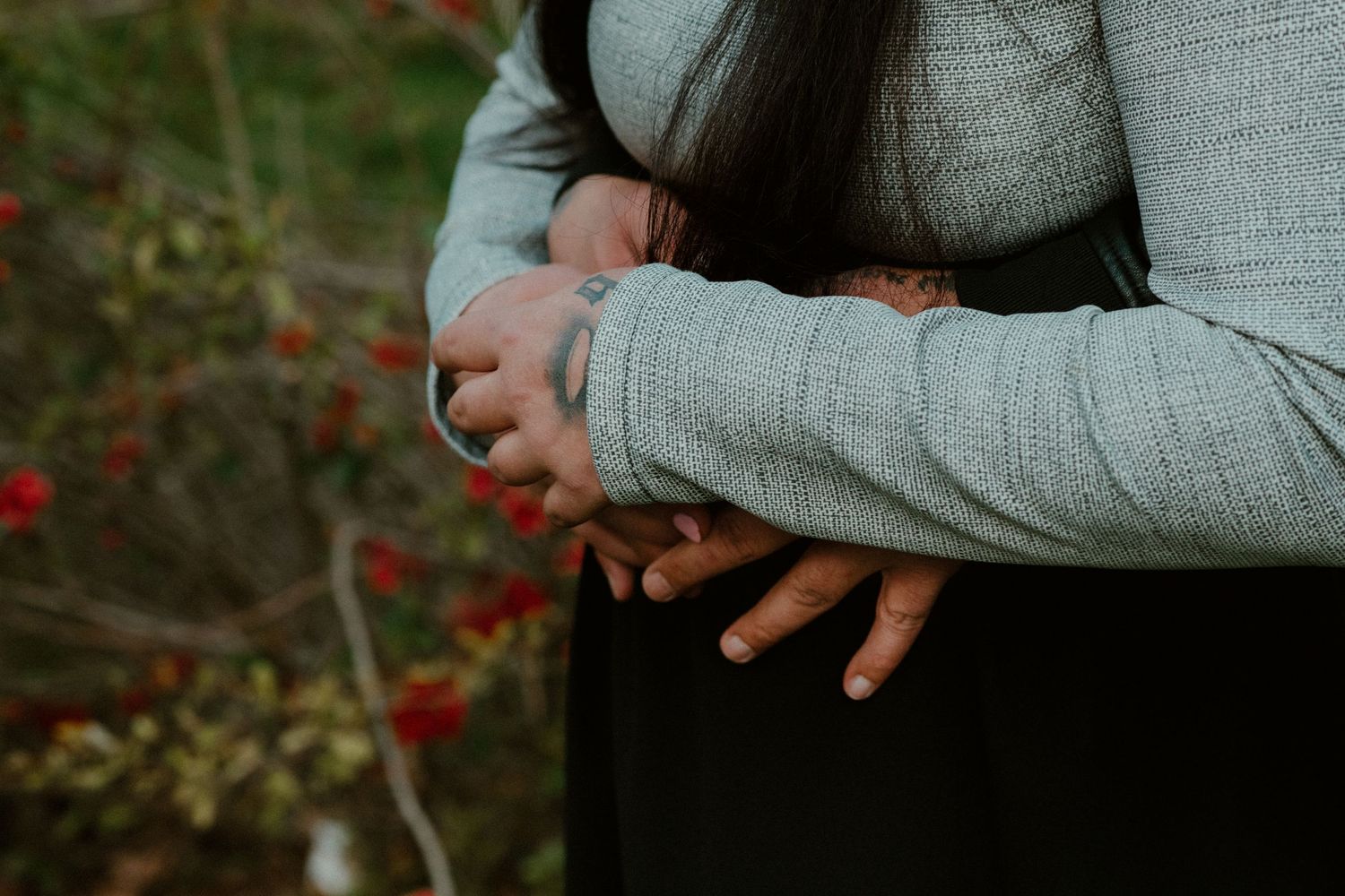 Close-up shot of hands clasped together wearing simple rings.