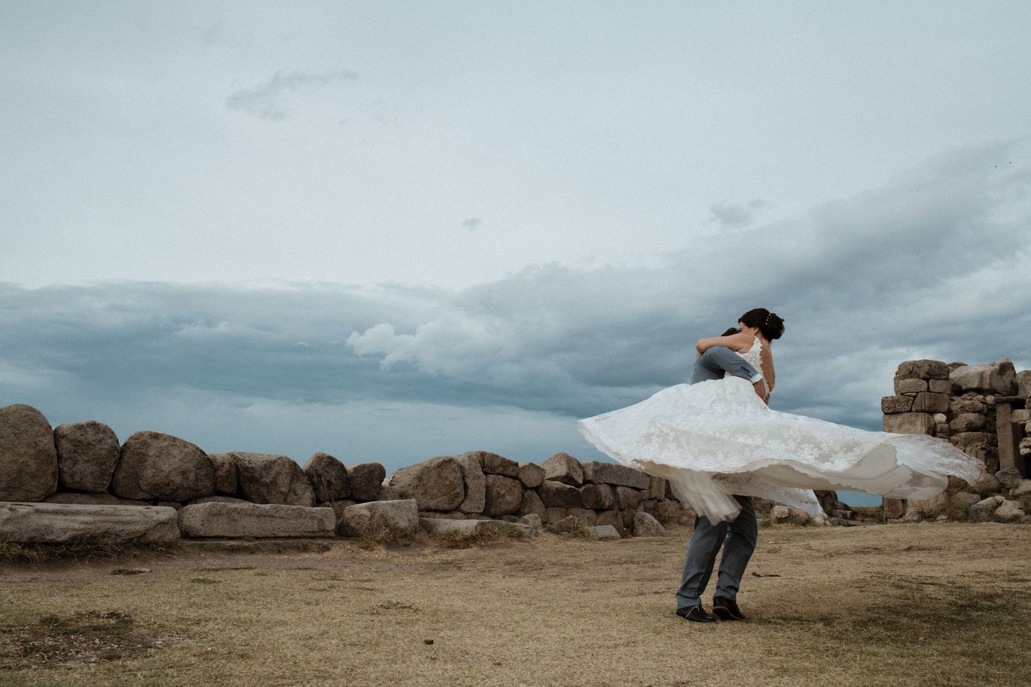 A white dress billowing in the wind against a rocky coastal landscape.
