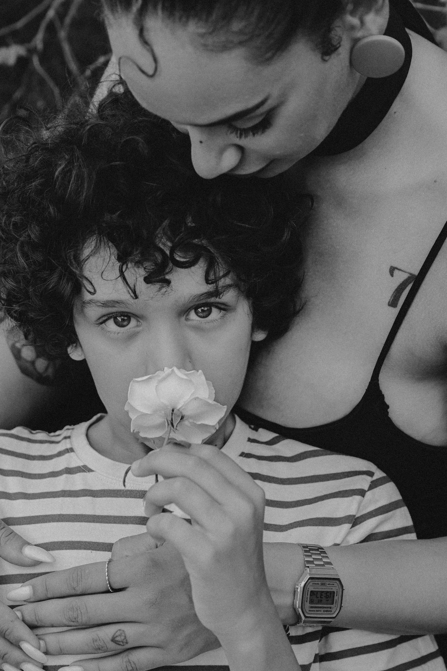 Black and white sequence showing a young person with curly hair holding a tissue to their nose while wearing a striped shirt.