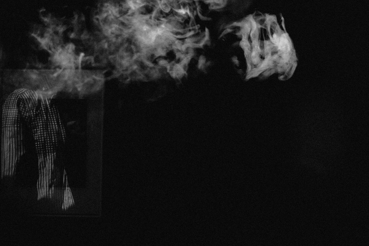 Dramatic black and white photo of smoke rising against dark background.