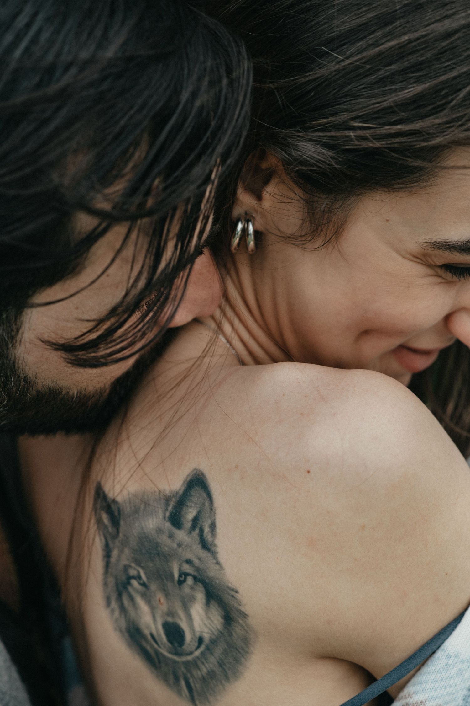 Close-up detail of a wolf tattoo on someone's shoulder during an intimate moment.
