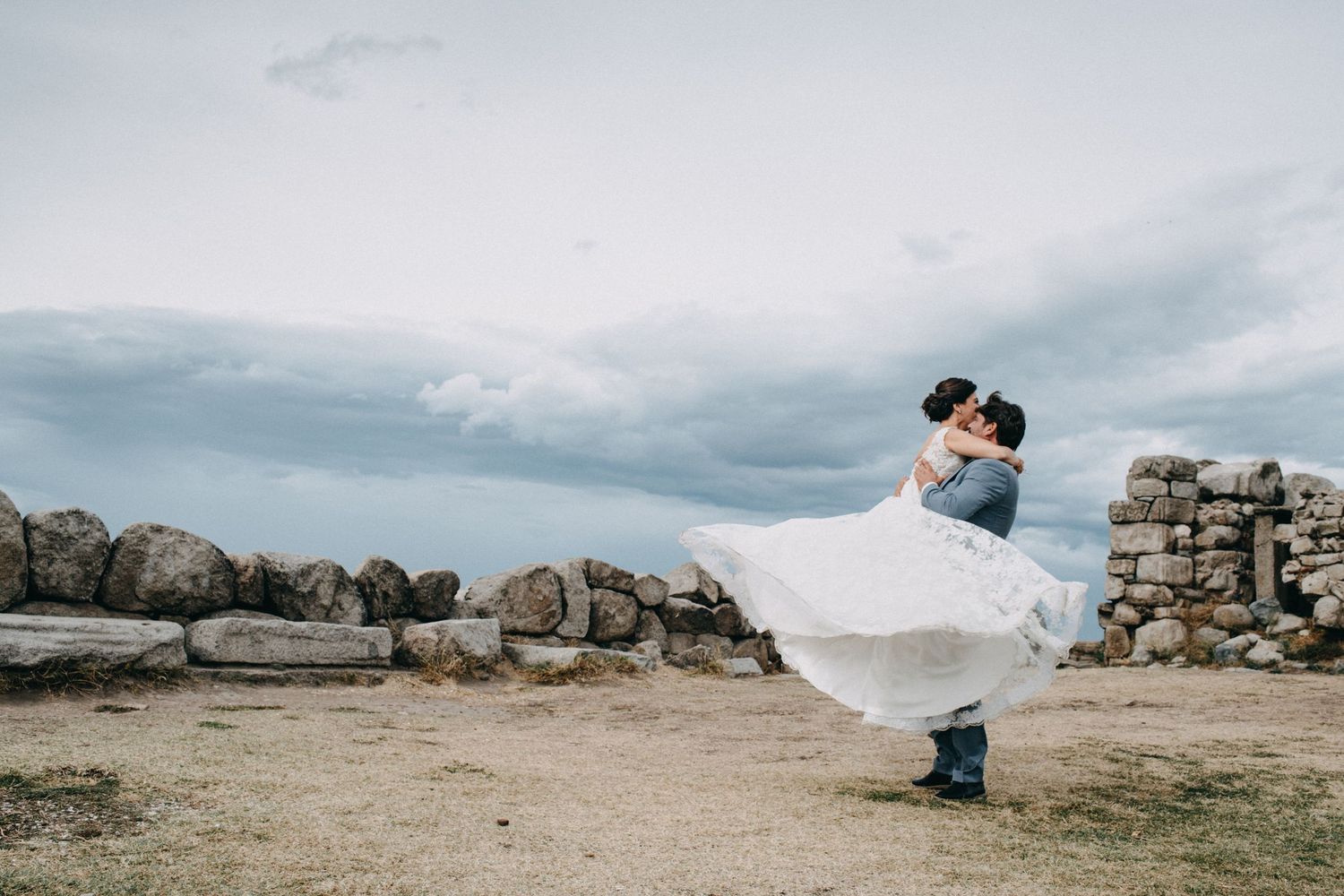 Panoramic wedding photos on a rocky coastal landscape with dramatic cloudy skies.
