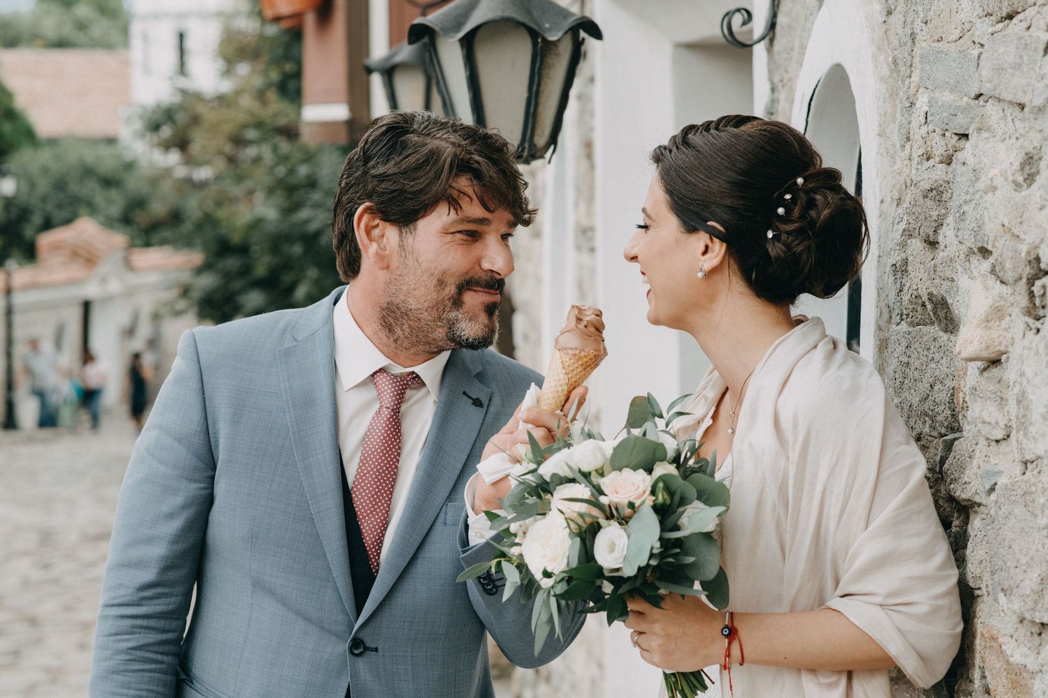 Elegant wedding couple sharing a romantic moment against a stone wall.
