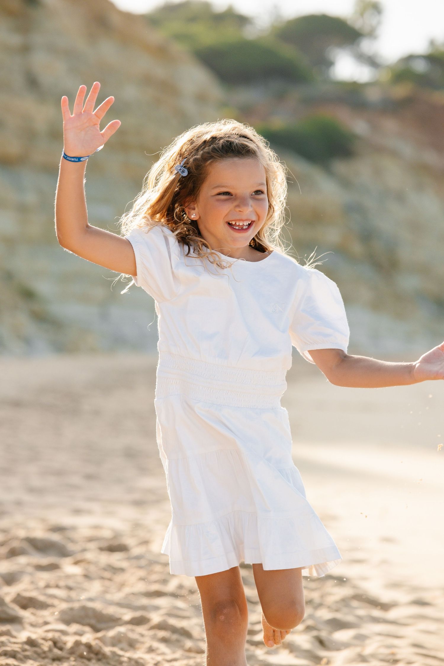 model daughter running on the beach in Portugal with a big smile