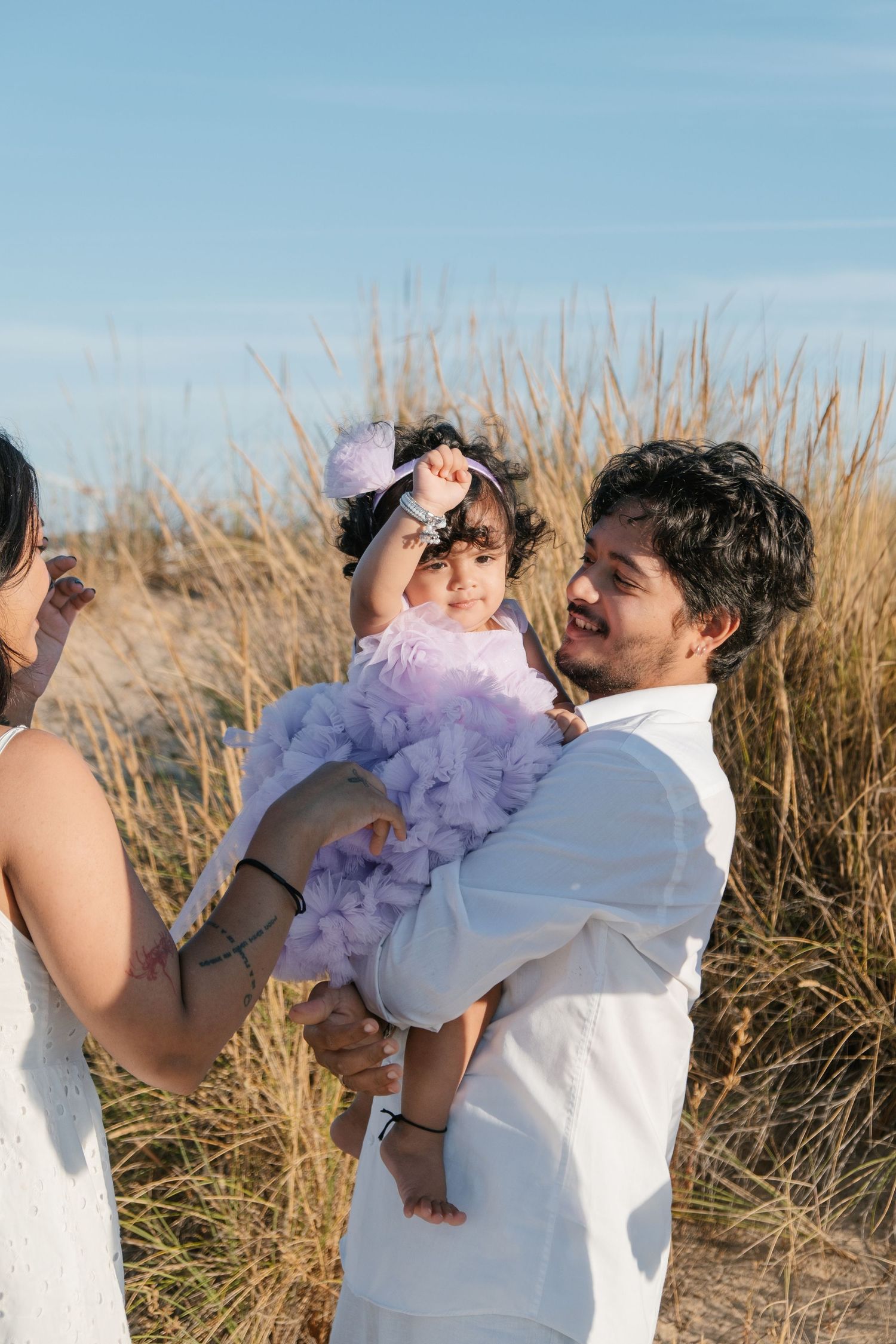 Parents holding their one-year-old at Meia Praia during sunrise.