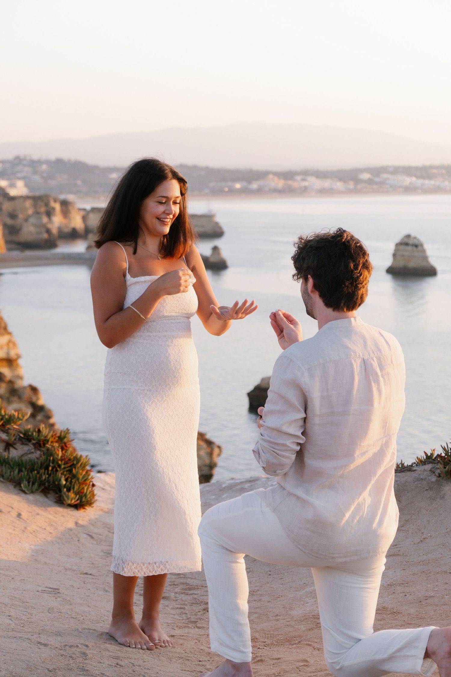 couple saying yes on Lagos cliffs at sunrise with sandstone formations behind — captured by Renske Photography