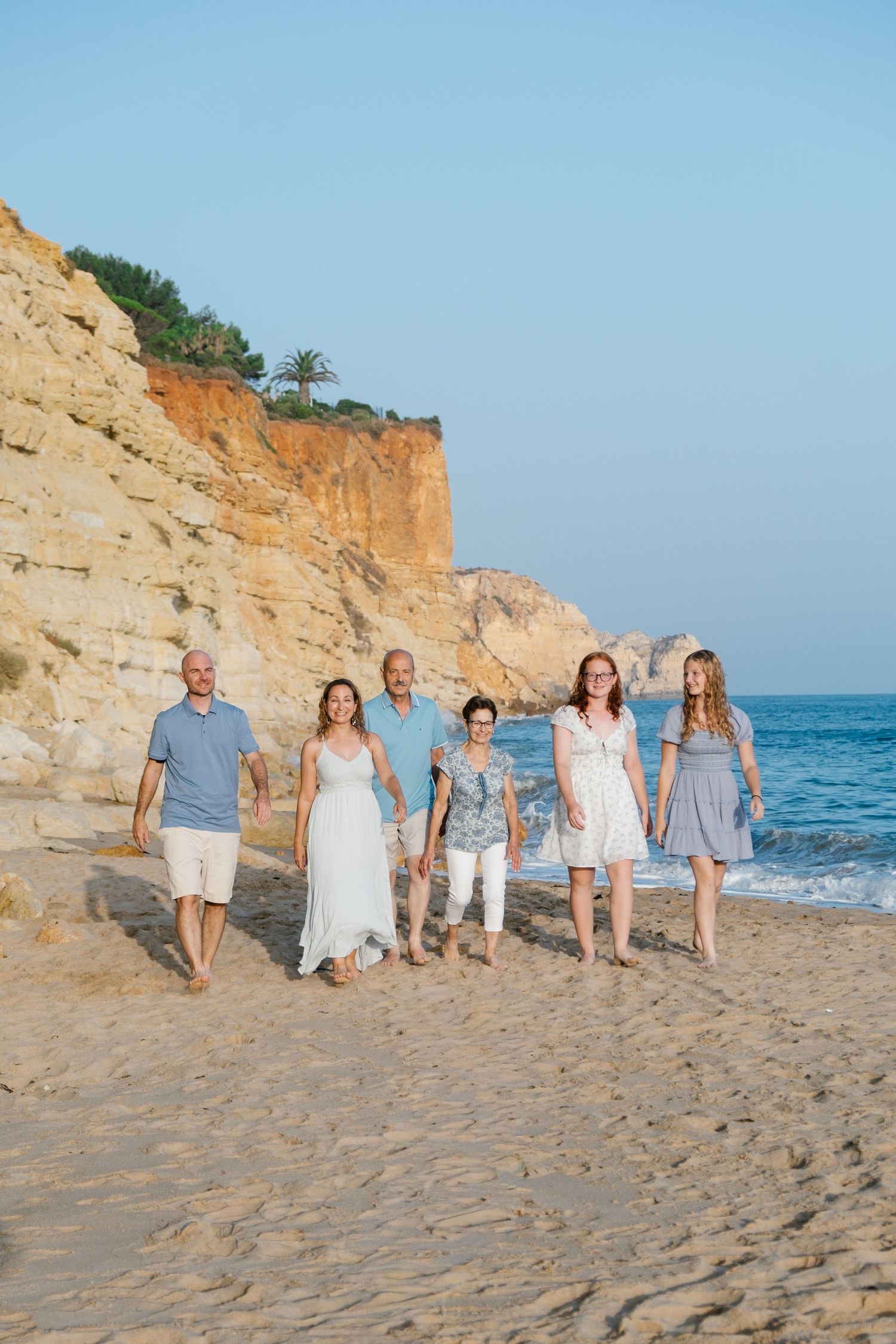 family walking along tidal pools at Praia Porto de Mós at sunset with reflections in water