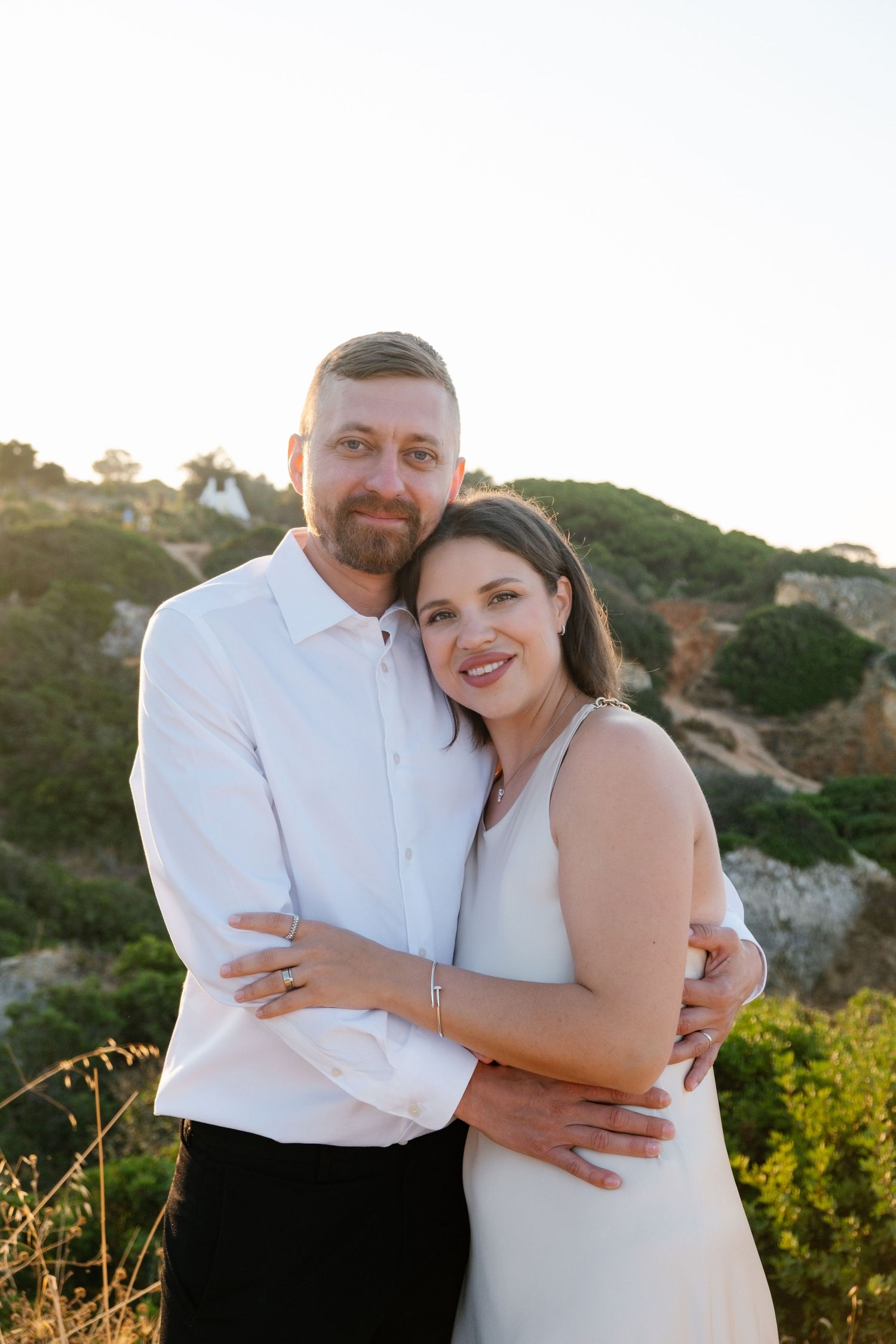 warm sunrise shot of couple embracing on cliff edge in Algarve Portugal