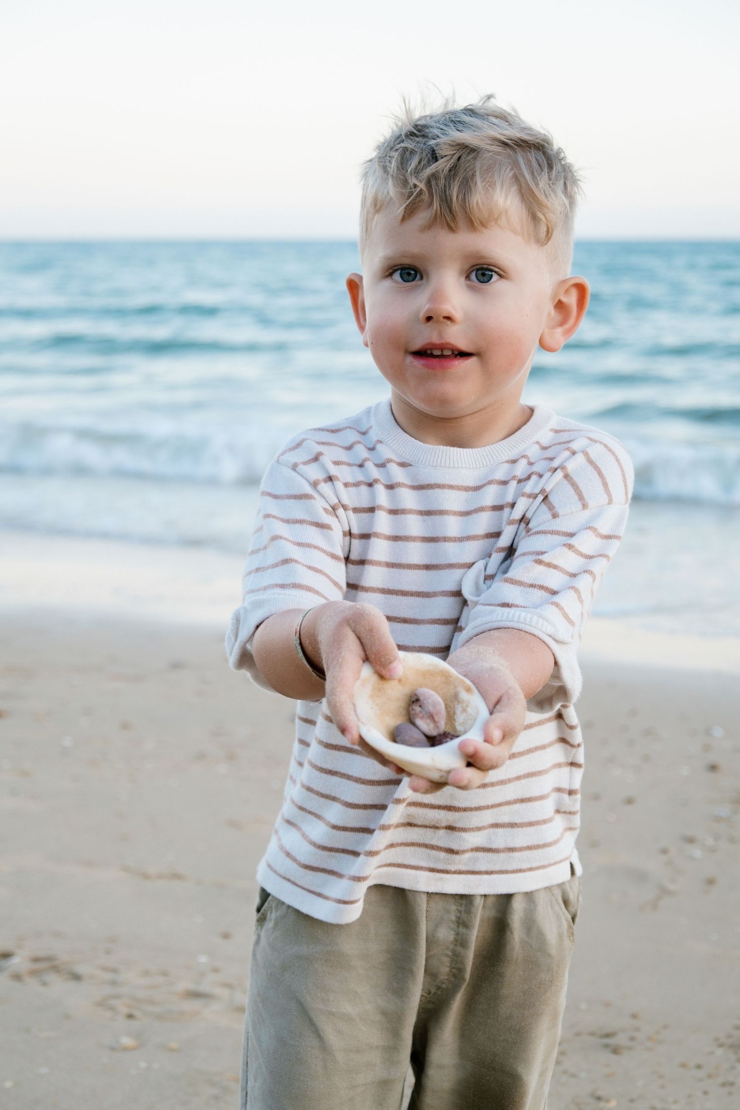 small boy showing his shelves from the beach