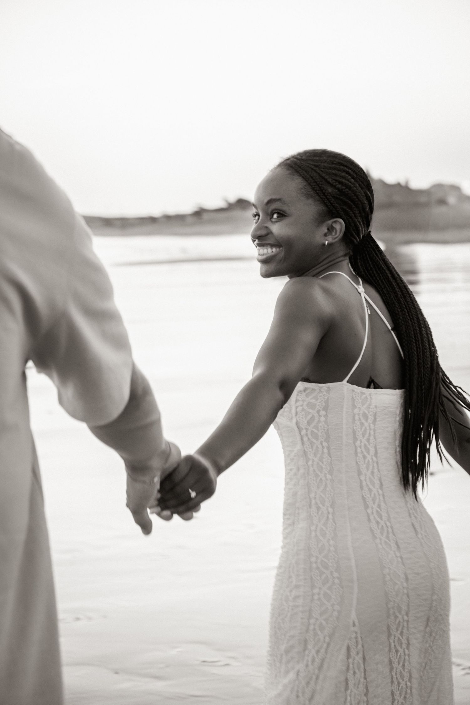 woman running on the beach, holding hands with her partner