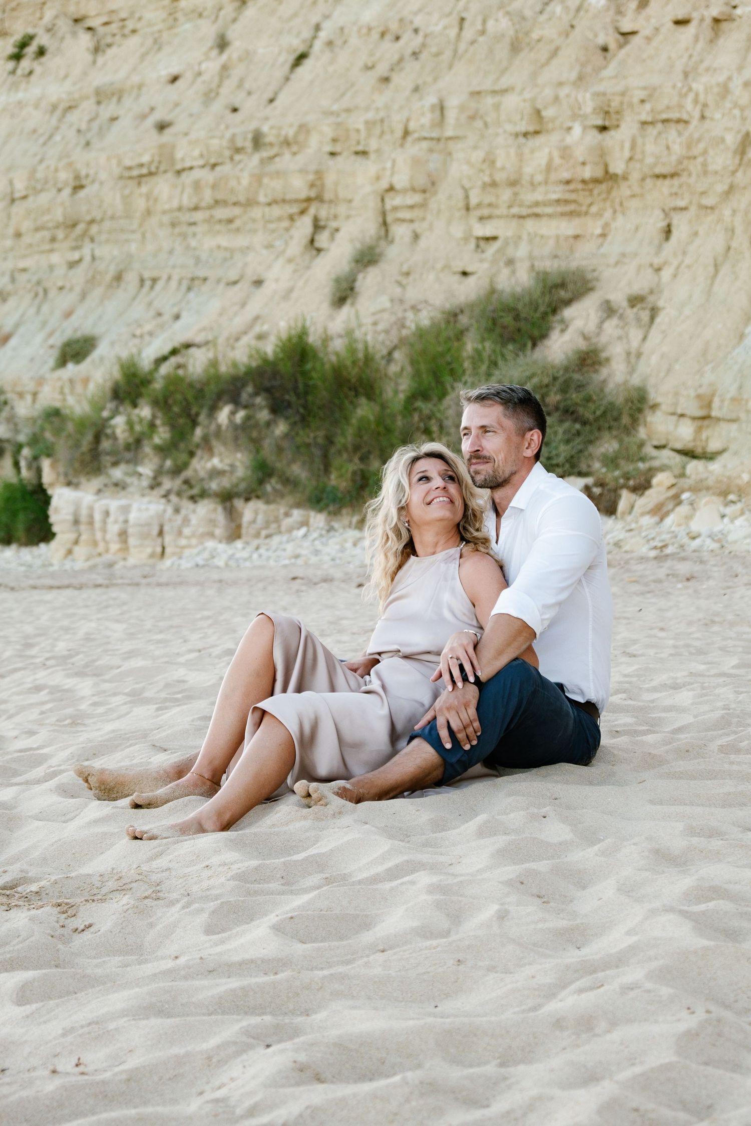 Couple sitting on the beach with gentle waves and warm evening light.