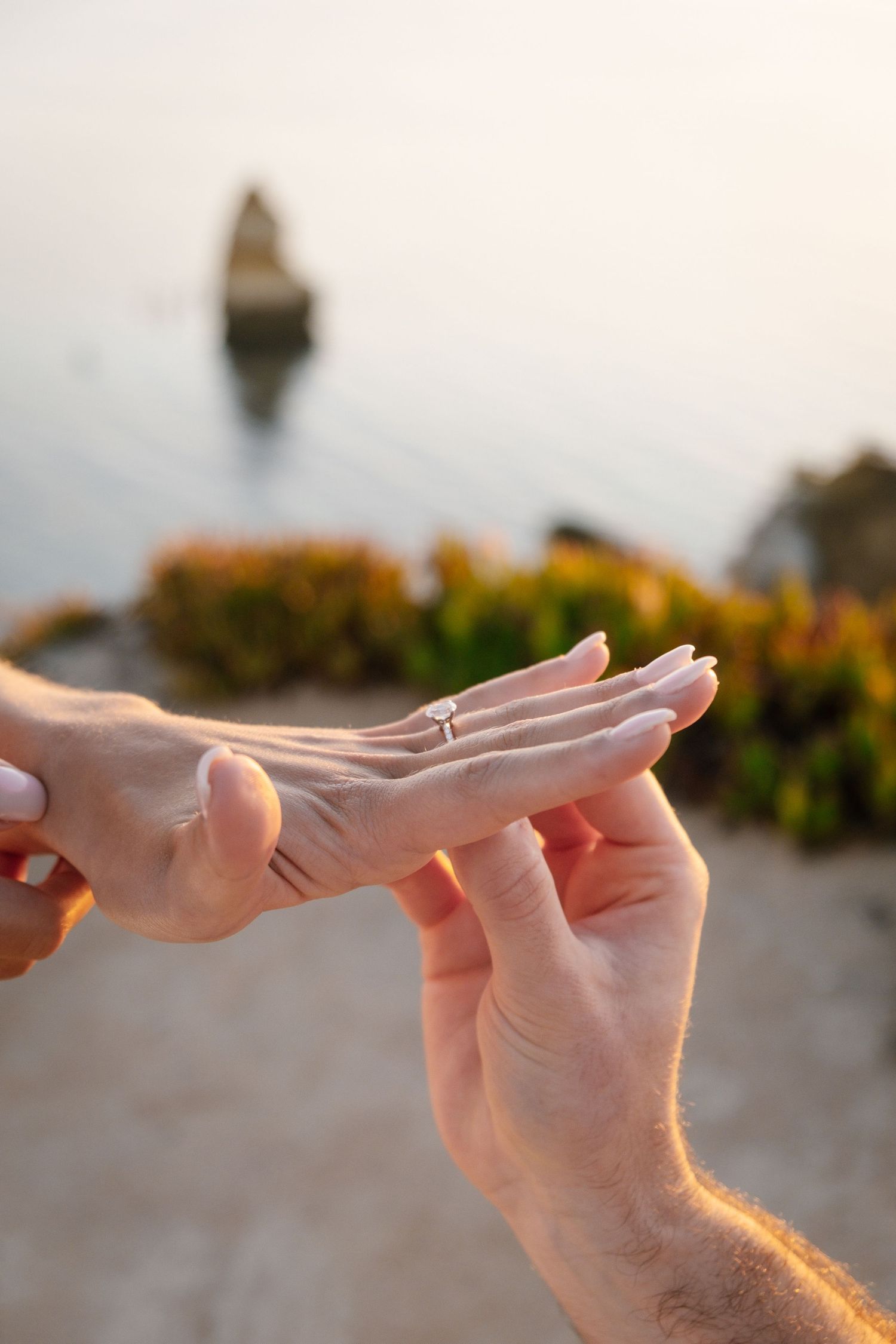 detailed photo of engagement ring on hand with ocean in background