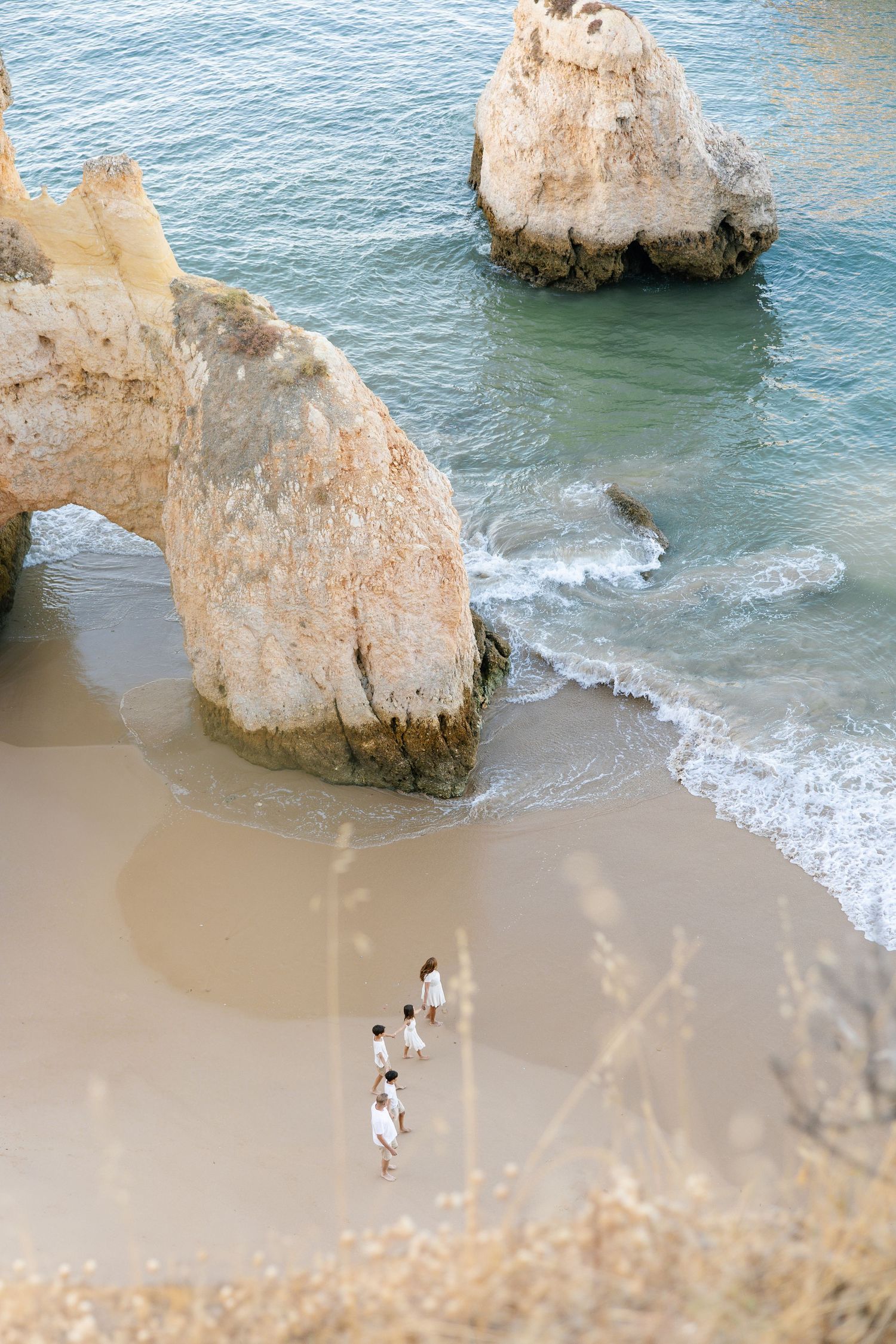 Candid family photoshoot at Três Irmãos beach with sandstone rock formations and ocean waves.