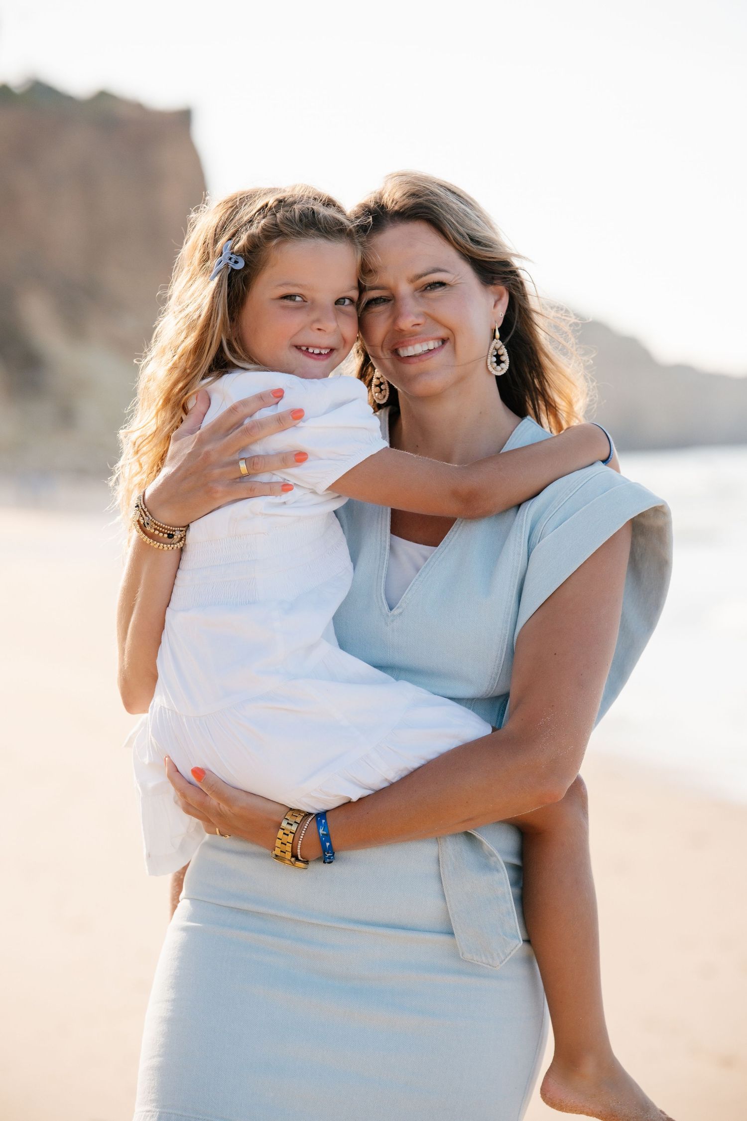 Mom holding daughter on the shoulder with blue dress and cute beautiful daughter