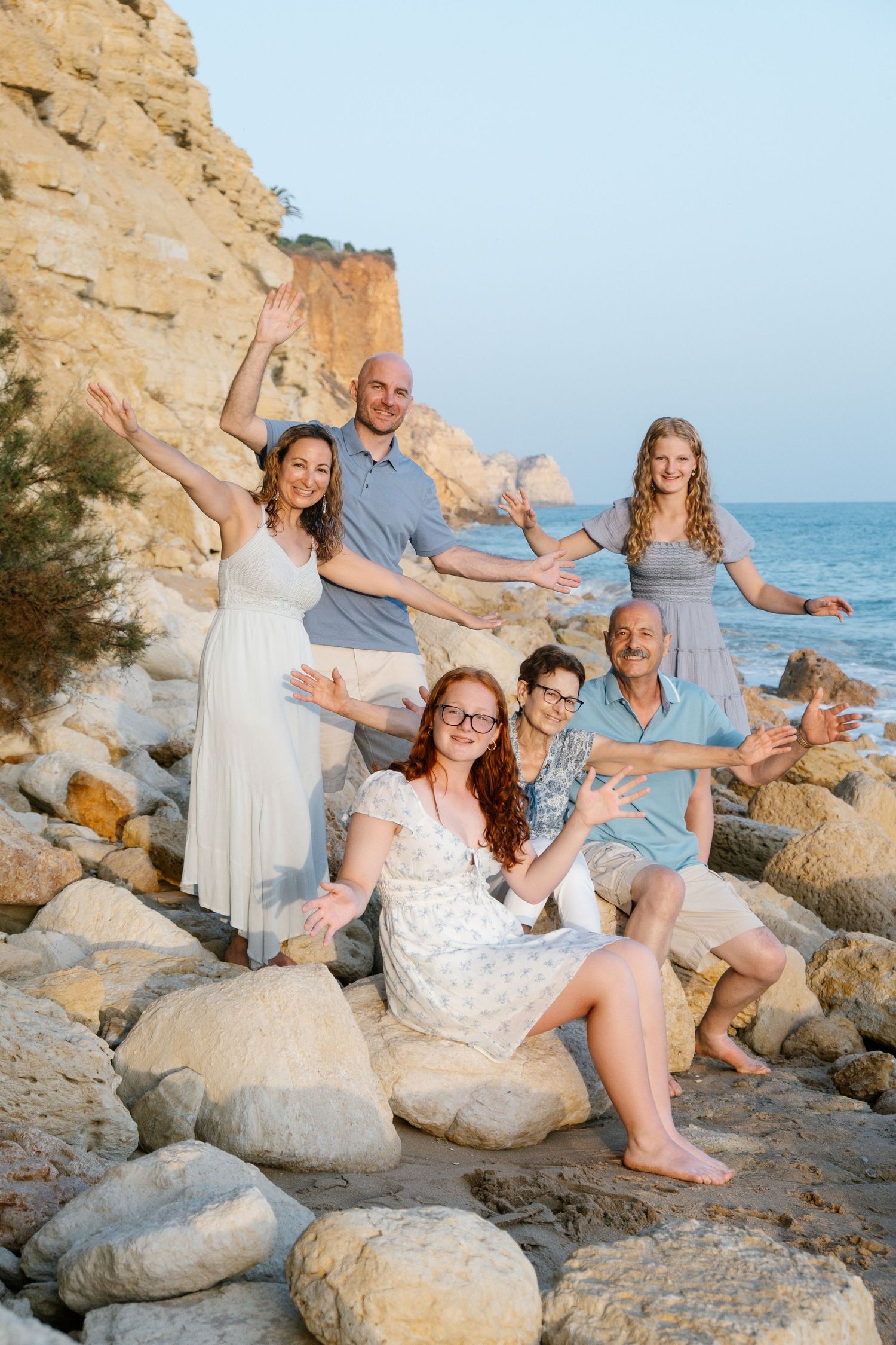 candid family moment sitting on beach rocks with golden cliffs in the background