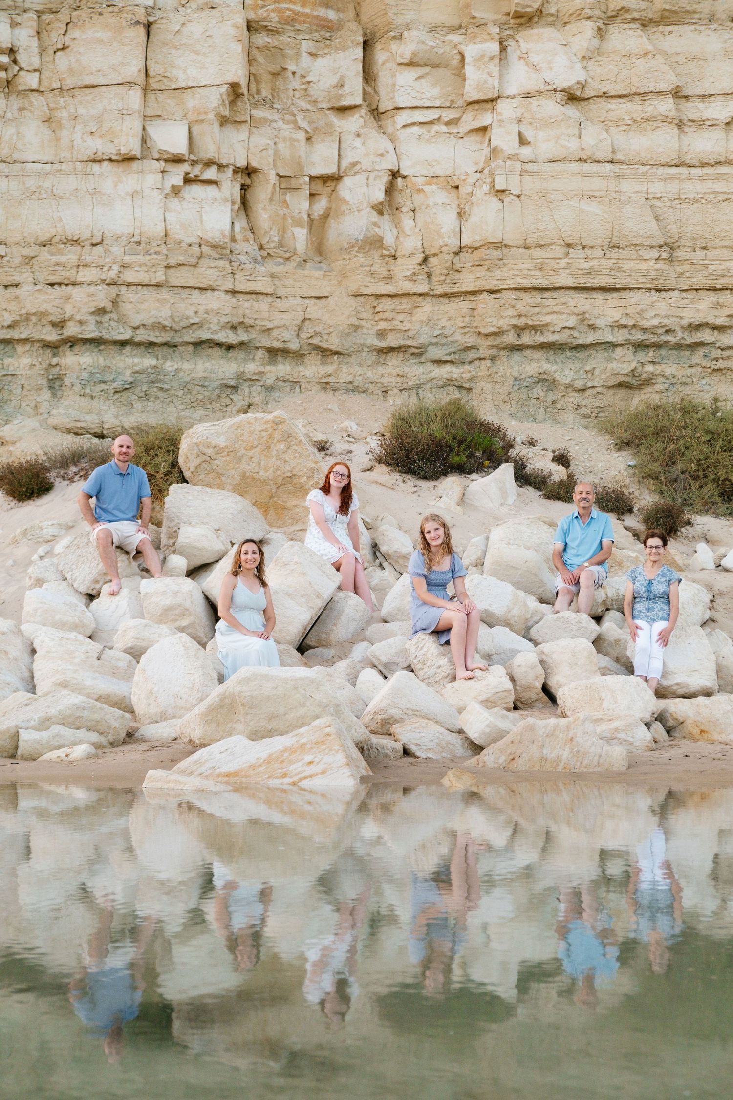 wide shot of family with cliffs and sunset reflected in tide pools at Porto de Mós Algarve