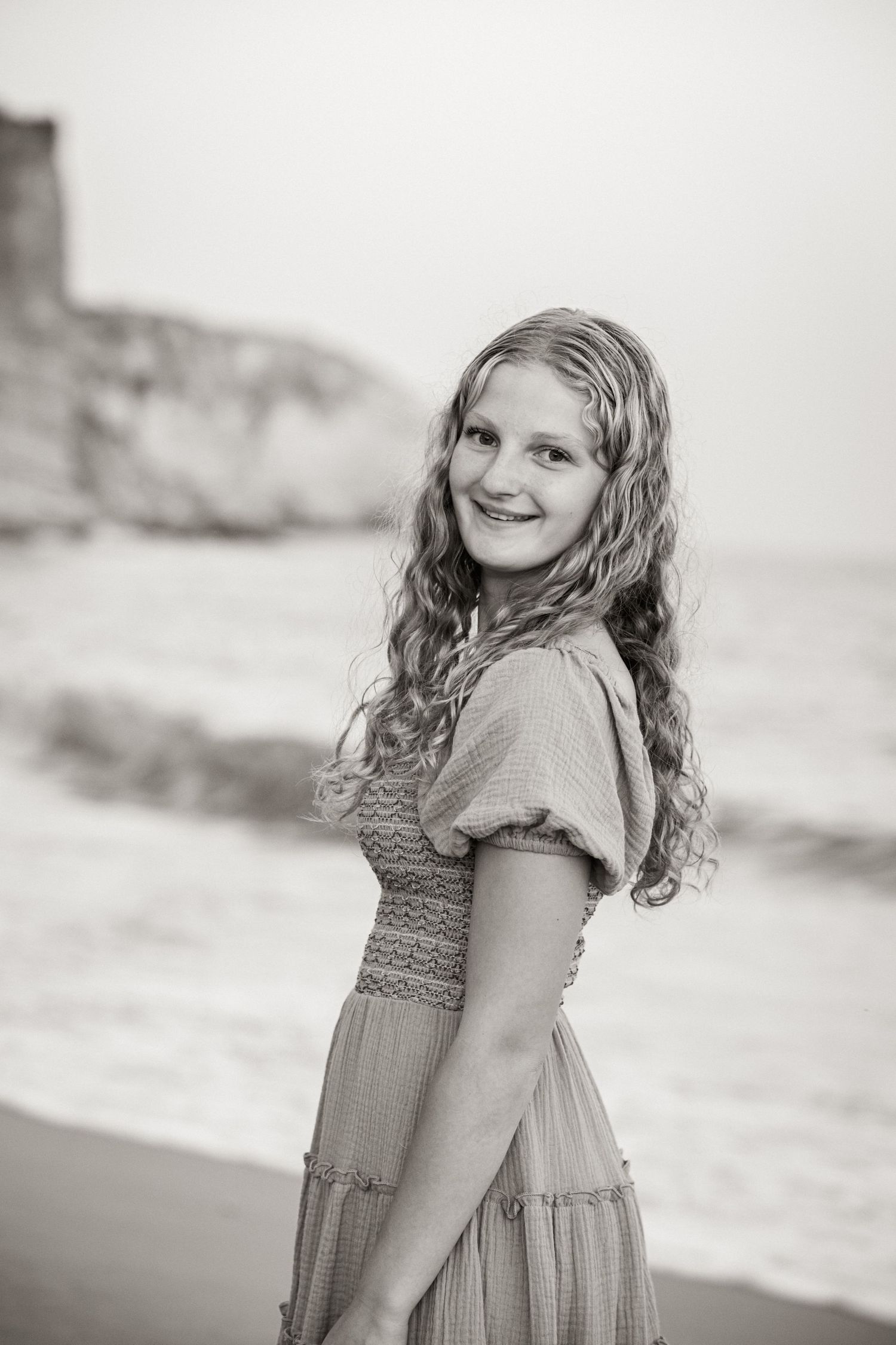 portrait of daughter with golden light and ocean waves blurred in background