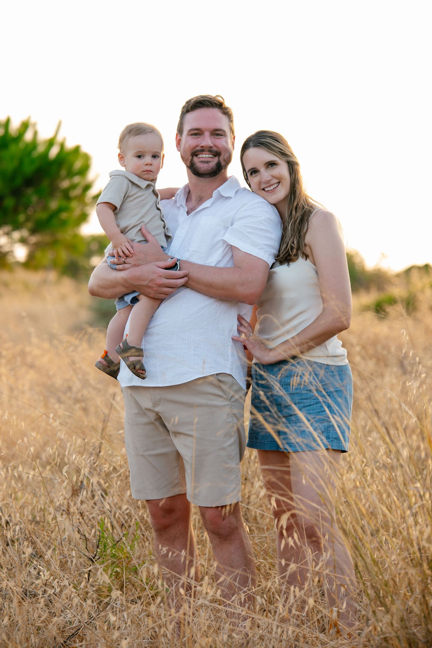 family standing in grassy field near Ponta da Piedade cliffs during golden hour